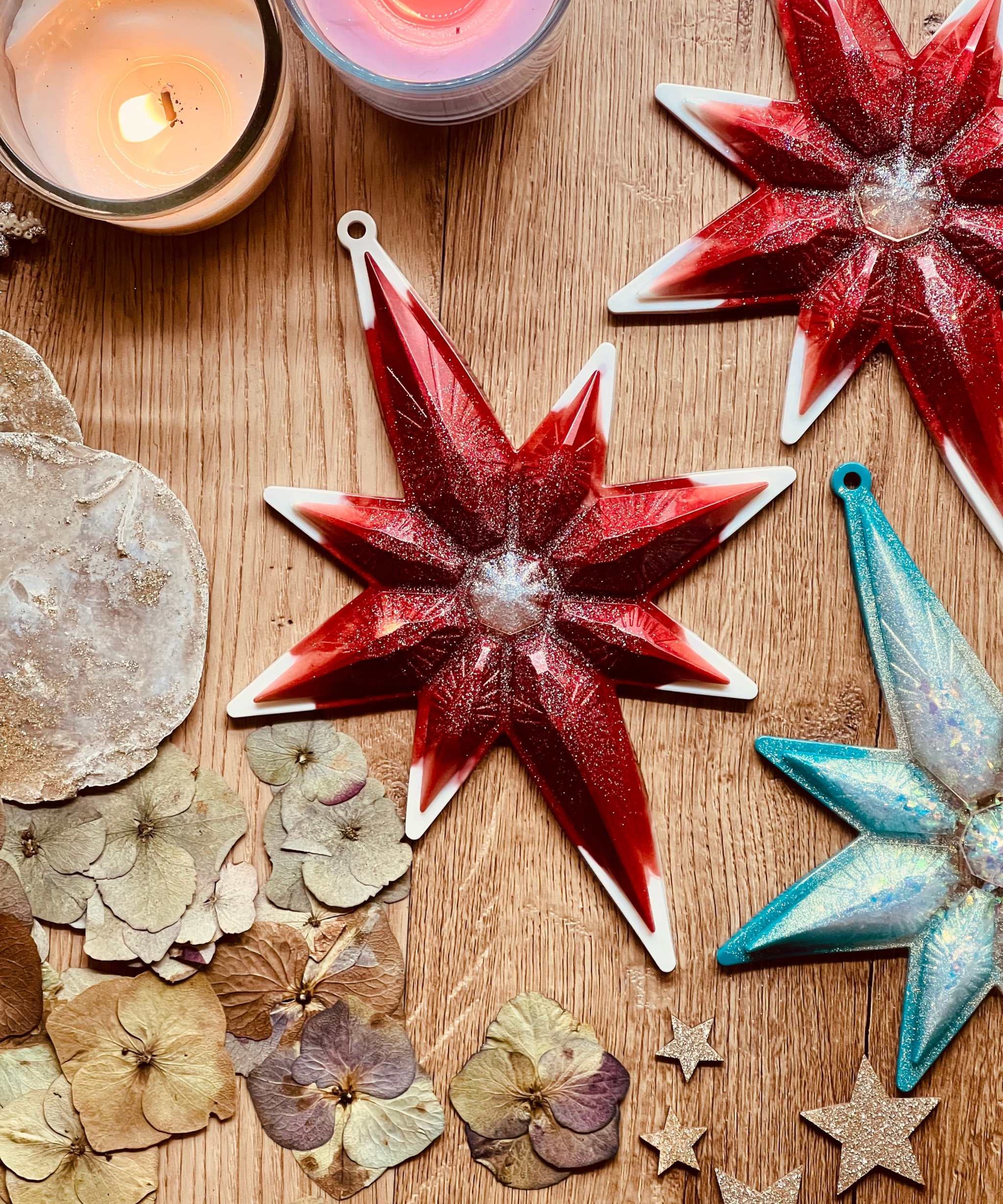 Handmade resin star-shaped Weihnachtsbaumanhänger in red and turquoise with white and silver accents.