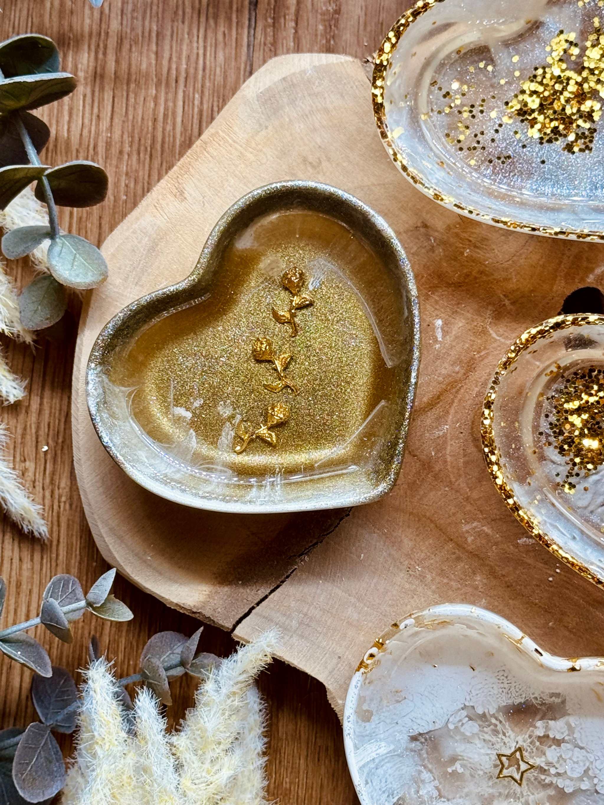 Herzförmige handgemachte Schmuckschale aus weißem Resin mit goldenen Details auf Holzuntergrund