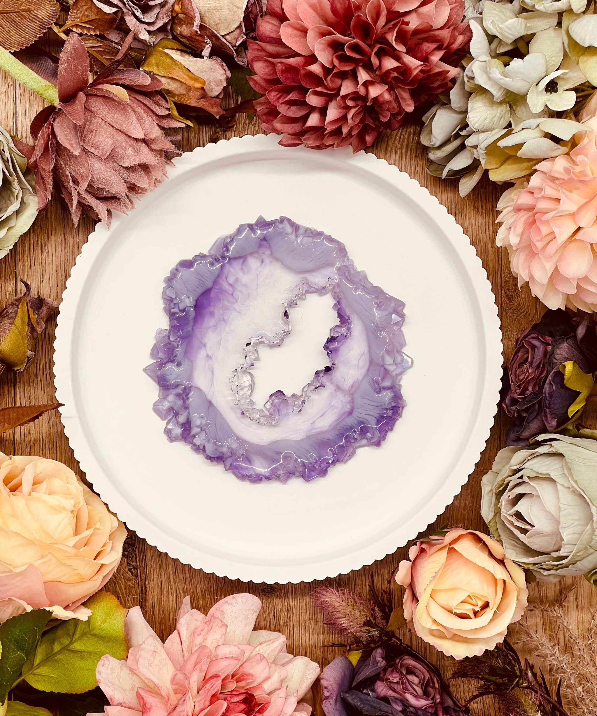 Tablett aus Resin im handgemachten Geode Kristall Design mit violettem Zentrum, umgeben von dekorativen Blumen auf Holztisch