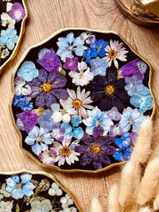 Handgemachtes Tablett aus Resin mit echten bunten Blumen und goldenen Details auf Holztisch