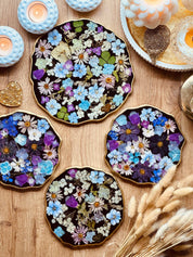 Handgemachtes Tablett aus Resin mit eingebetteten bunten Blumen und goldenen Details auf Holztisch