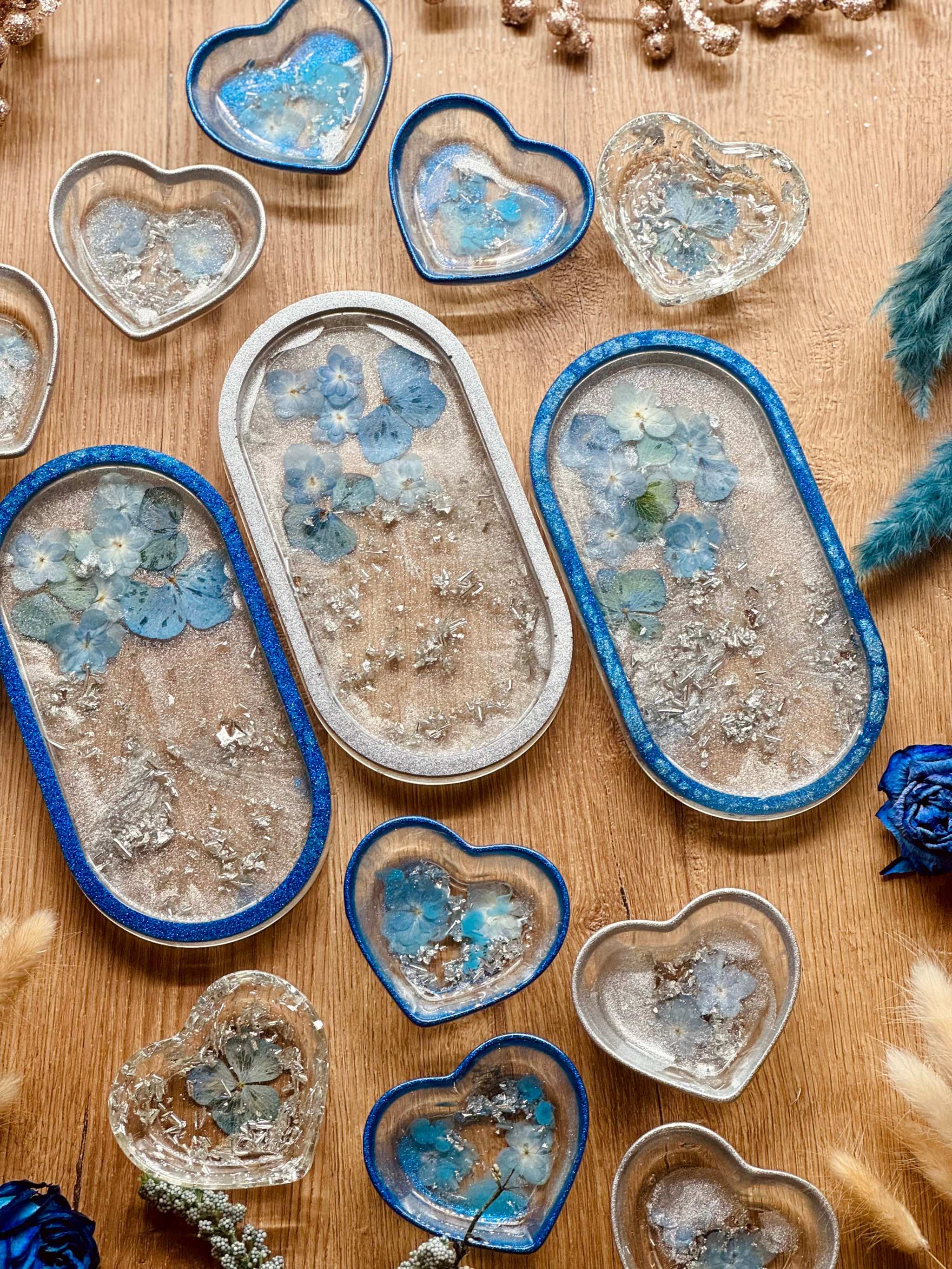 Handgemachte Schmuckschalen aus Resin in Blau und Silber mit eingegossenen Blumen in unterschiedlichen Herz- und Ovalformen