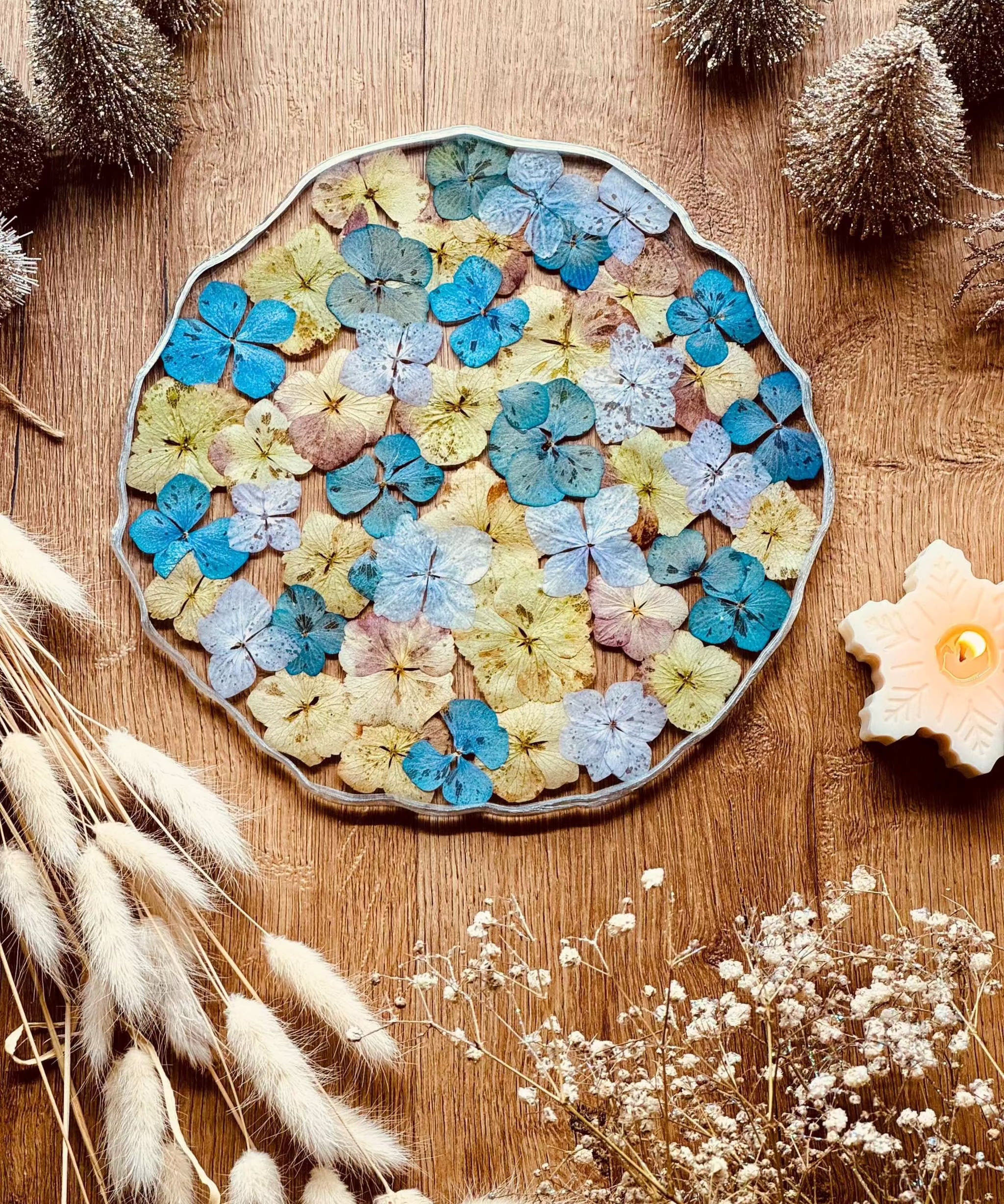 rundes handgemachtes Tablett aus Resin mit bunten Hortensien und silbernen Details auf Holztisch