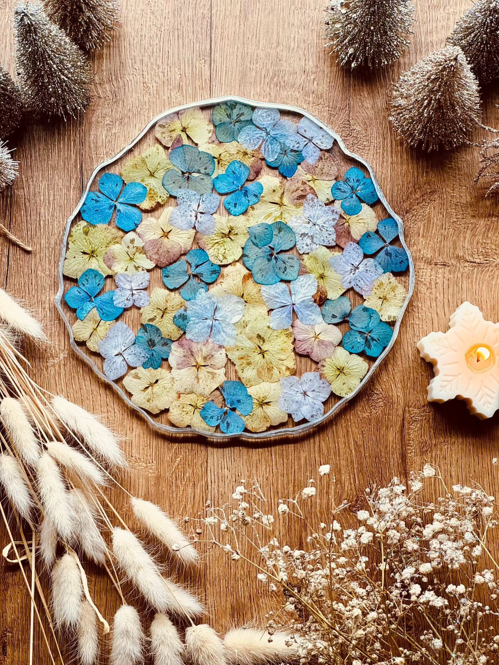 rundes handgemachtes Tablett aus Resin mit bunten Hortensien und silbernen Details auf Holztisch