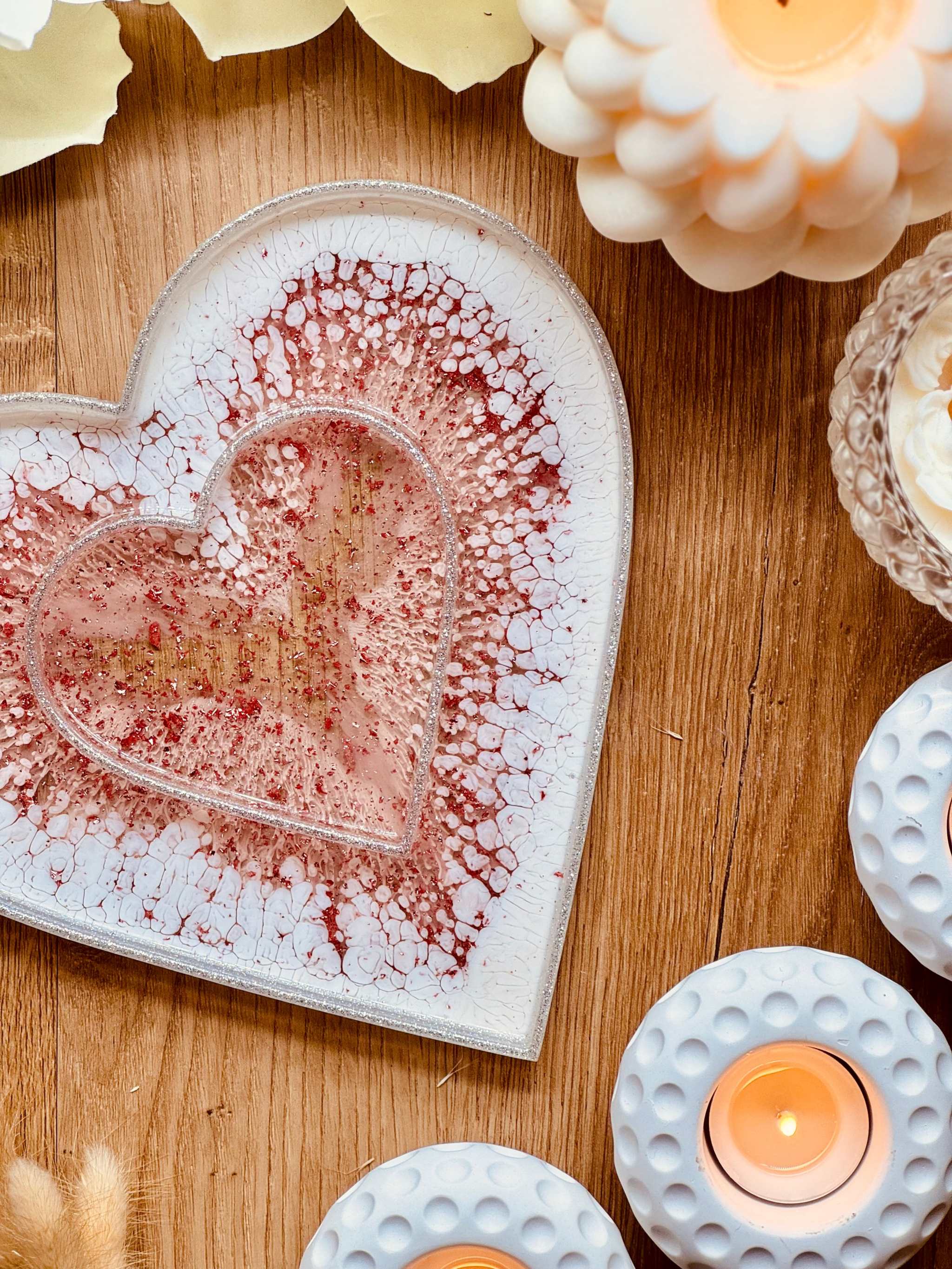 Herzförmiges rosa Resin Tablett mit silbernen 3D Details auf Holz mit Kerzen dekoriert