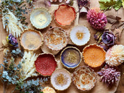 Mehrere handgemachte Schmuckschalen aus Resin in verschiedenen Farben mit goldenen Details, umgeben von Blumen und Deko.