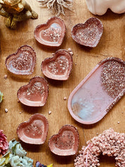 Handgemachte rosa Schmuckschalen aus Resin mit silbernem Glitzer in Herz- und Ovalform auf Holztisch