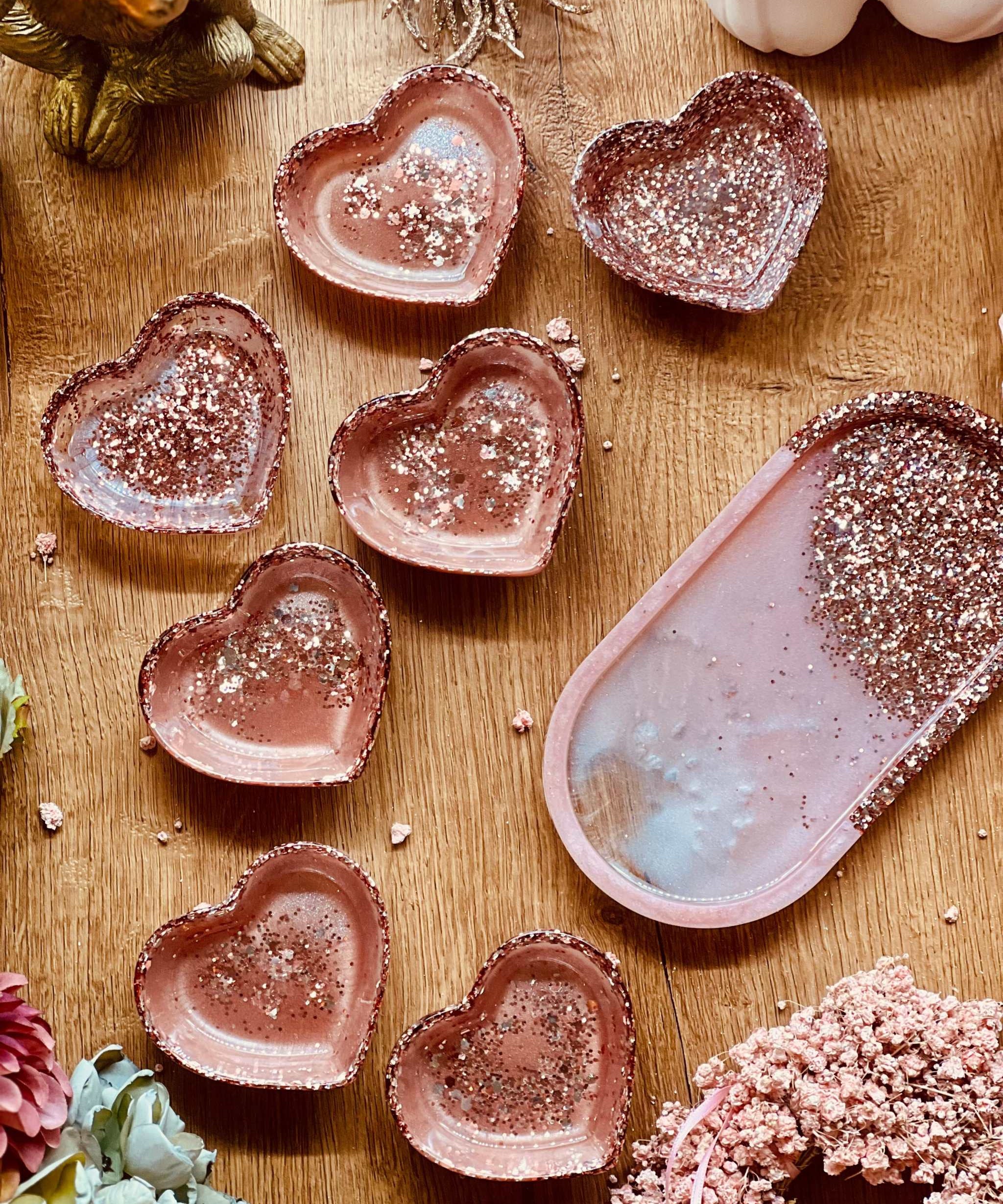 Handgemachte rosa Schmuckschalen aus Resin mit silbernem Glitzer in Herz- und Ovalform auf Holztisch