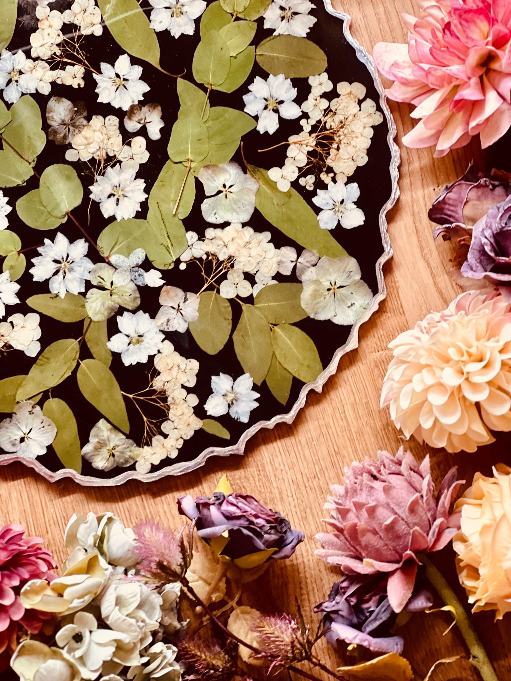 Schwarzes handgemachtes Resin Tablett mit Eukalyptus, Hortensien und silbernen Details auf Holztisch