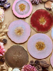 Handgemachte Tabletts aus Resin in rosa, rot und braun mit goldenen Details auf Holztisch dekoriert