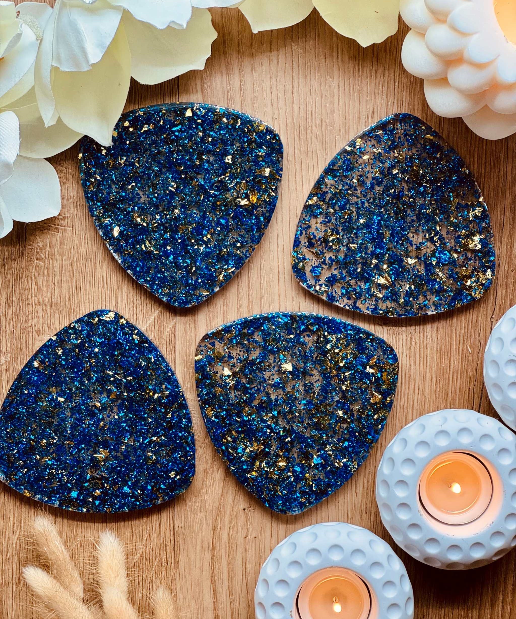 4 handgemachte blaue Resin Untersetzer mit goldenen Details auf Holztisch mit Kerzen und Blumen dekoriert