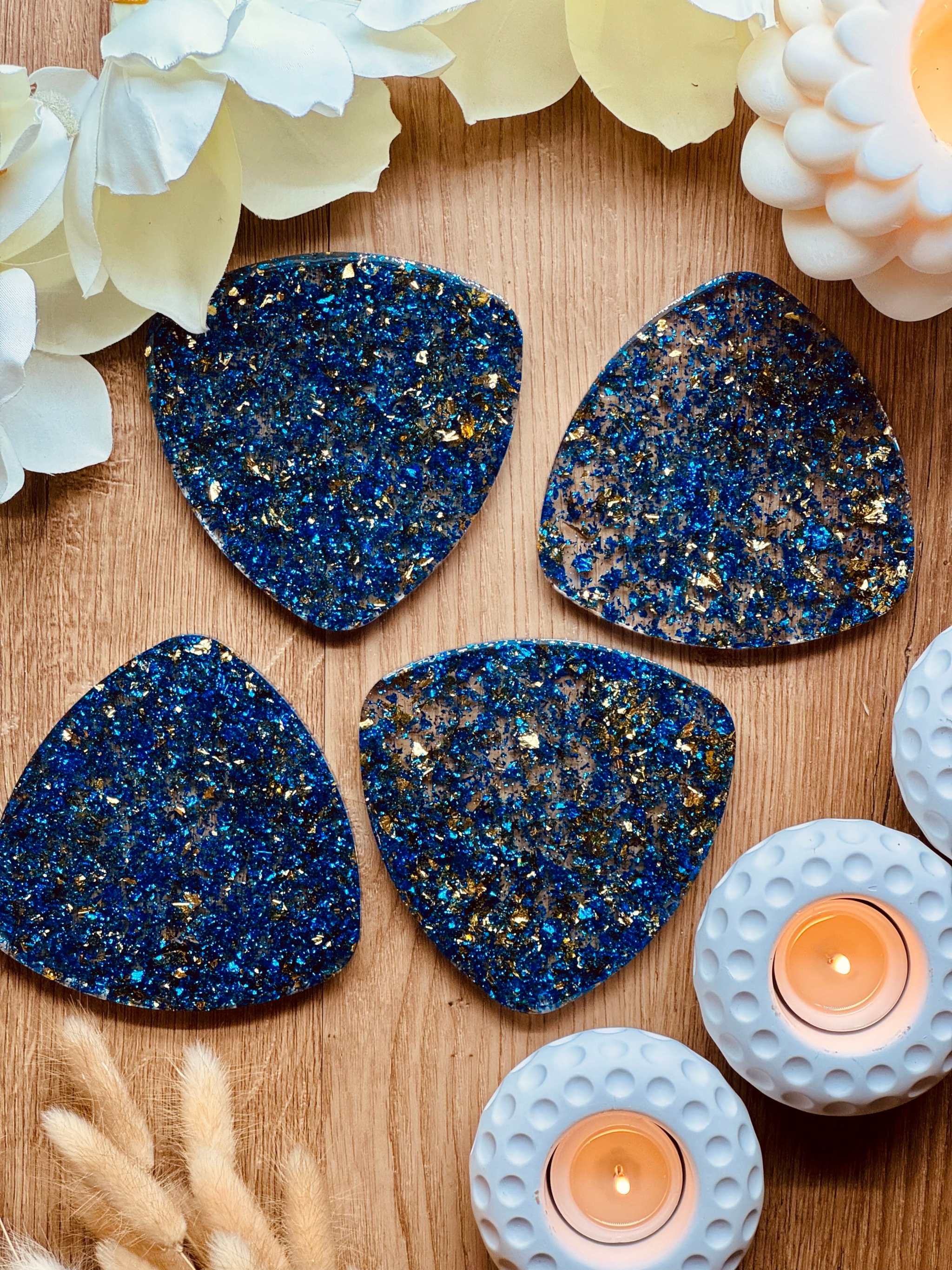 4 handgemachte blaue Resin Untersetzer mit goldenen Details auf Holztisch mit Kerzen und Blumen dekoriert