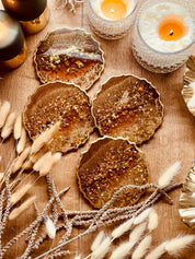 4 handgemachte braune Resin Untersetzer mit goldenen Details als dekoratives Set auf Holztisch