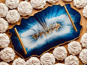 Handgemachtes blau-weißes Resin-Tablett mit goldenen Details und dekorativen Griffen, umgeben von weißen Rosen aus Gips.