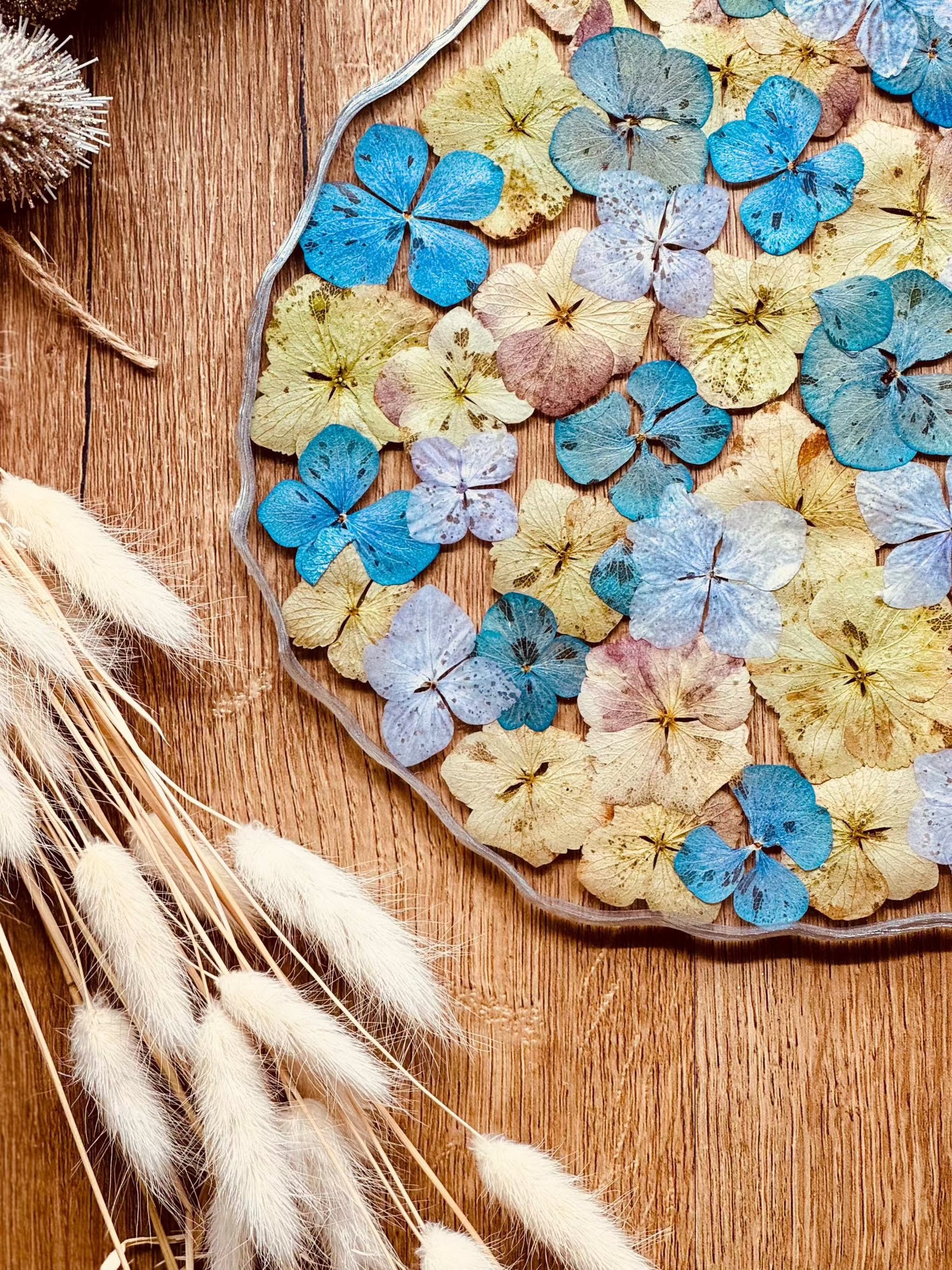 Handgemachtes Tablett aus Resin mit blauen und gelben Hortensien und silbernen Details auf Holzuntergrund