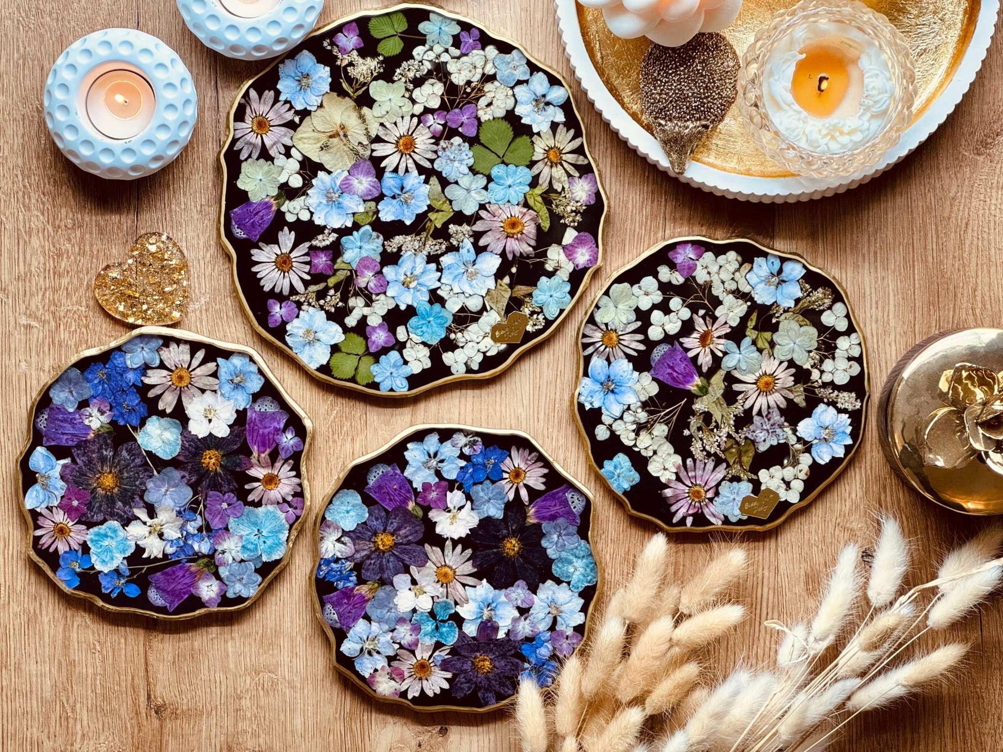 Handgemachte Tabletts aus Resin mit getrockneten Blumen und goldenen Details auf Holzuntergrund