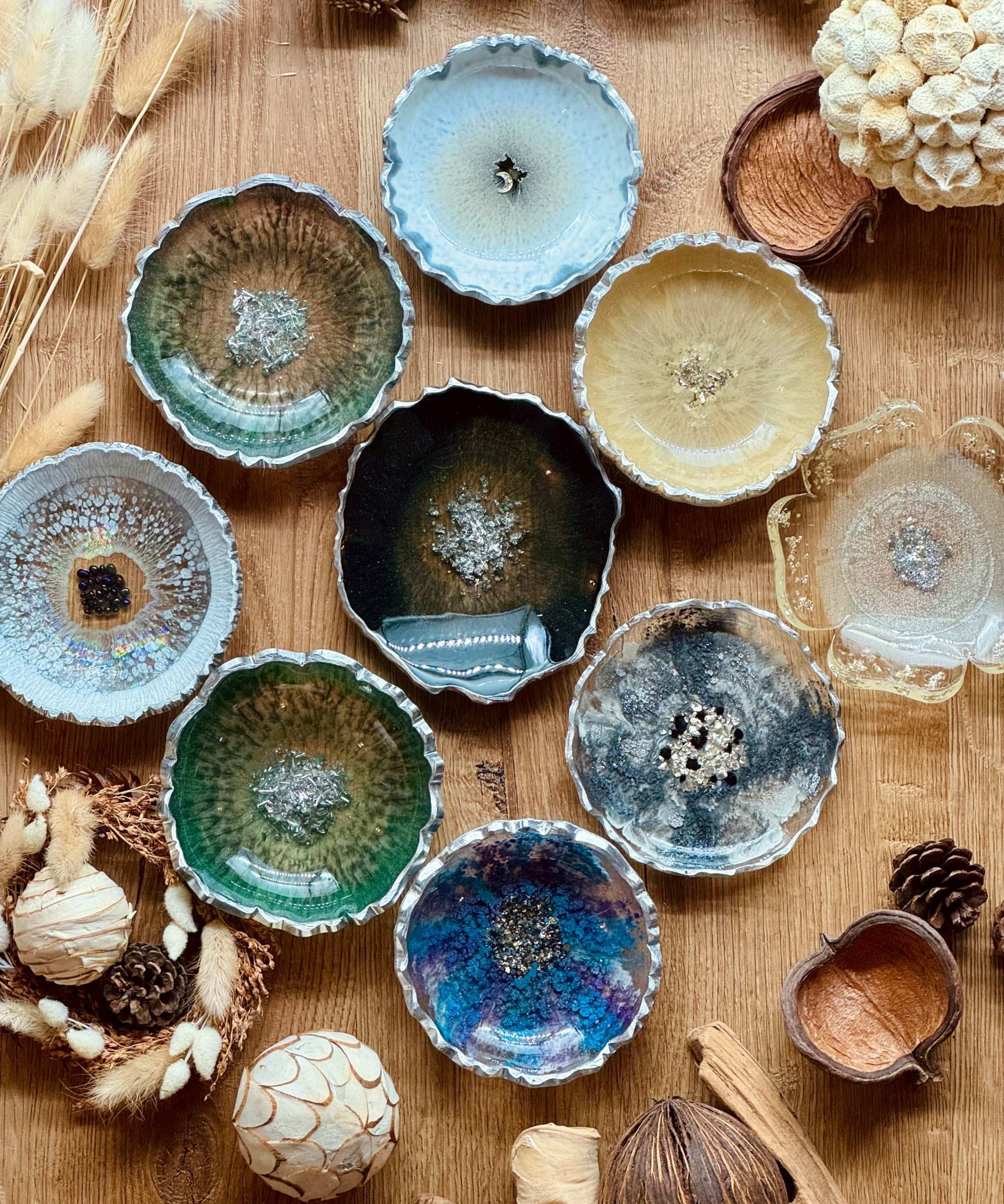 bunte handgemachte Schmuckschalen aus Resin mit silbernen Details auf Holztisch dekoriert