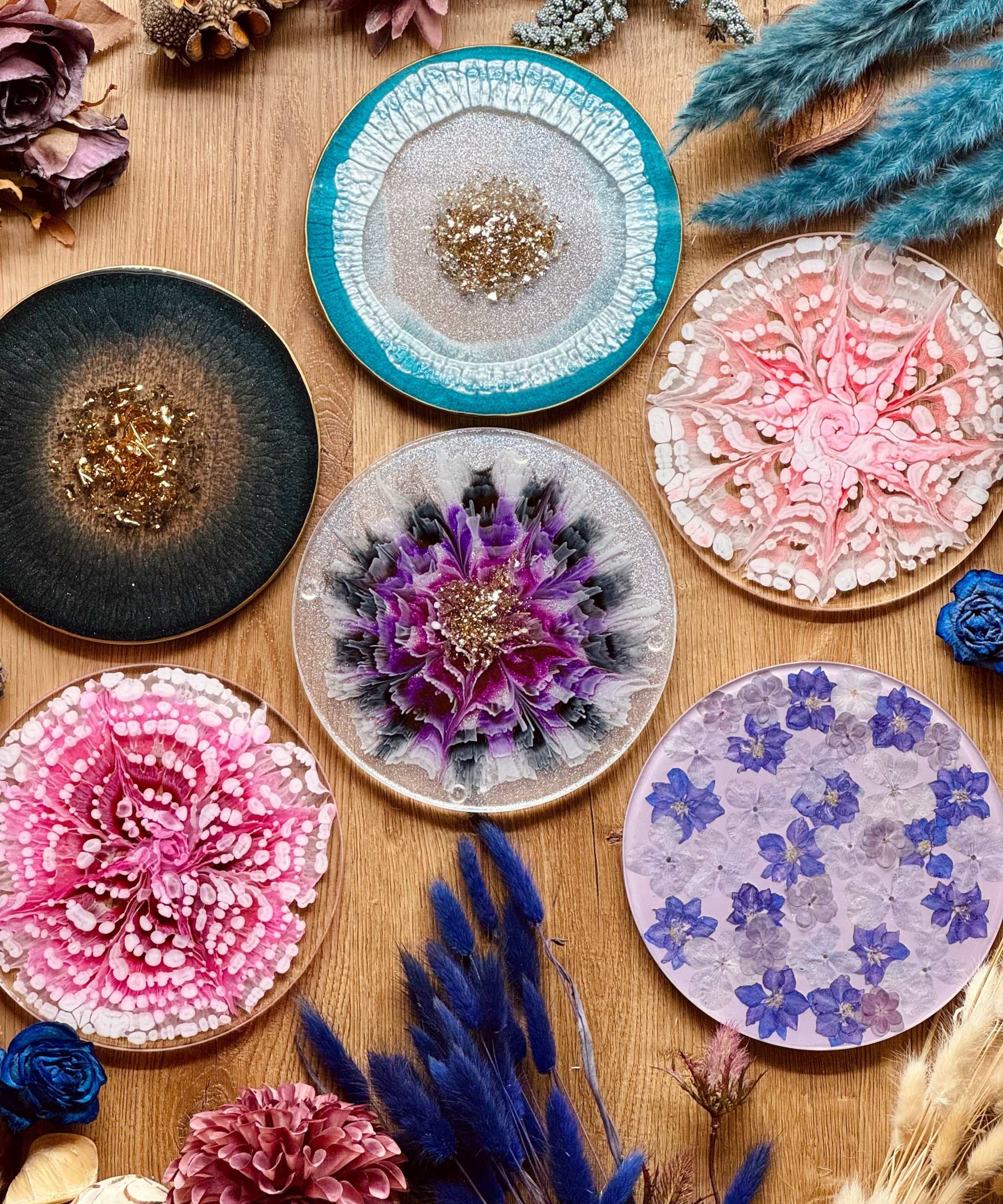 bunte handgemachte Tabletts aus Resin mit goldenen Details und floralem Design auf Holztisch