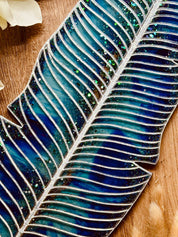 Handgemachtes türkis-blaues Tablett aus Resin in Blätterform mit silbernen Details auf Holzuntergrund