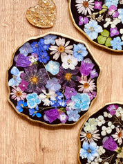 Handgemachtes Tablett aus Resin mit getrockneten Blumen und goldenen Details auf Holzhintergrund