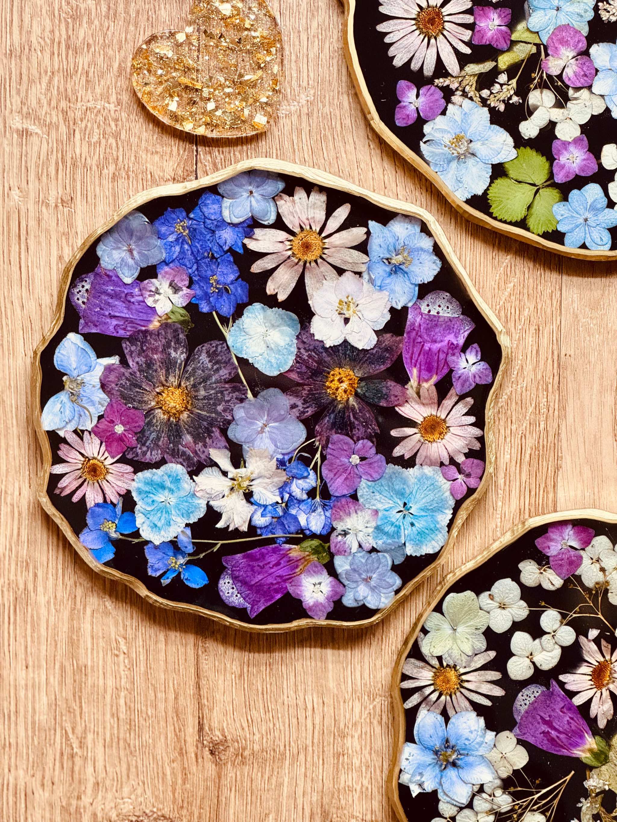 Handgemachtes Tablett aus Resin mit getrockneten Blumen und goldenen Details auf Holzhintergrund