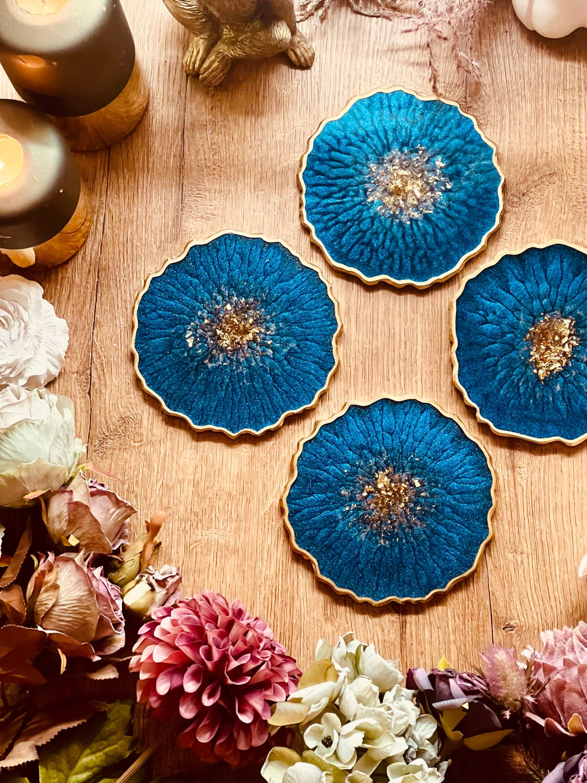 4 Untersetzer aus Resin in Blau mit goldenen Details handgemacht auf Holztisch mit Blumen und Kerzen dekoriert