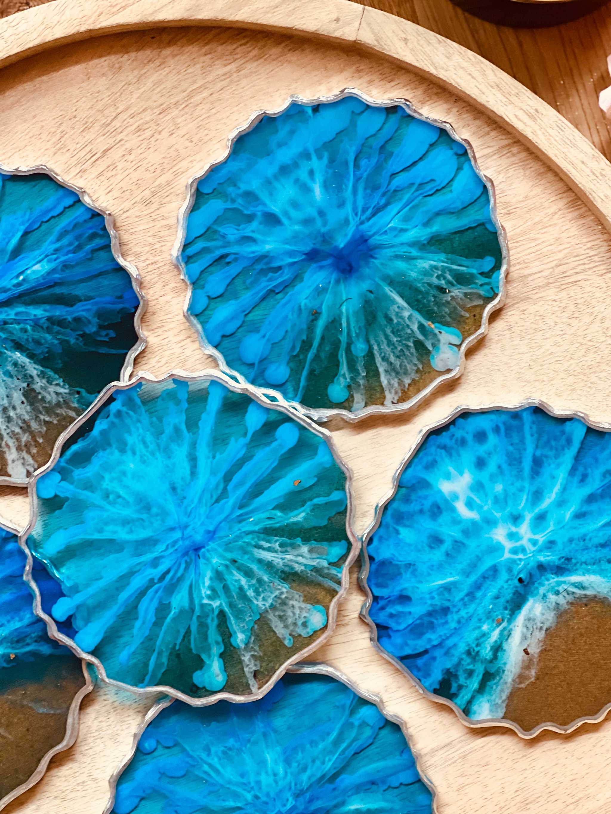 6 handgemachte blaue Untersetzer aus Resin mit silbernen Details im Ocean Design auf Holzunterlage