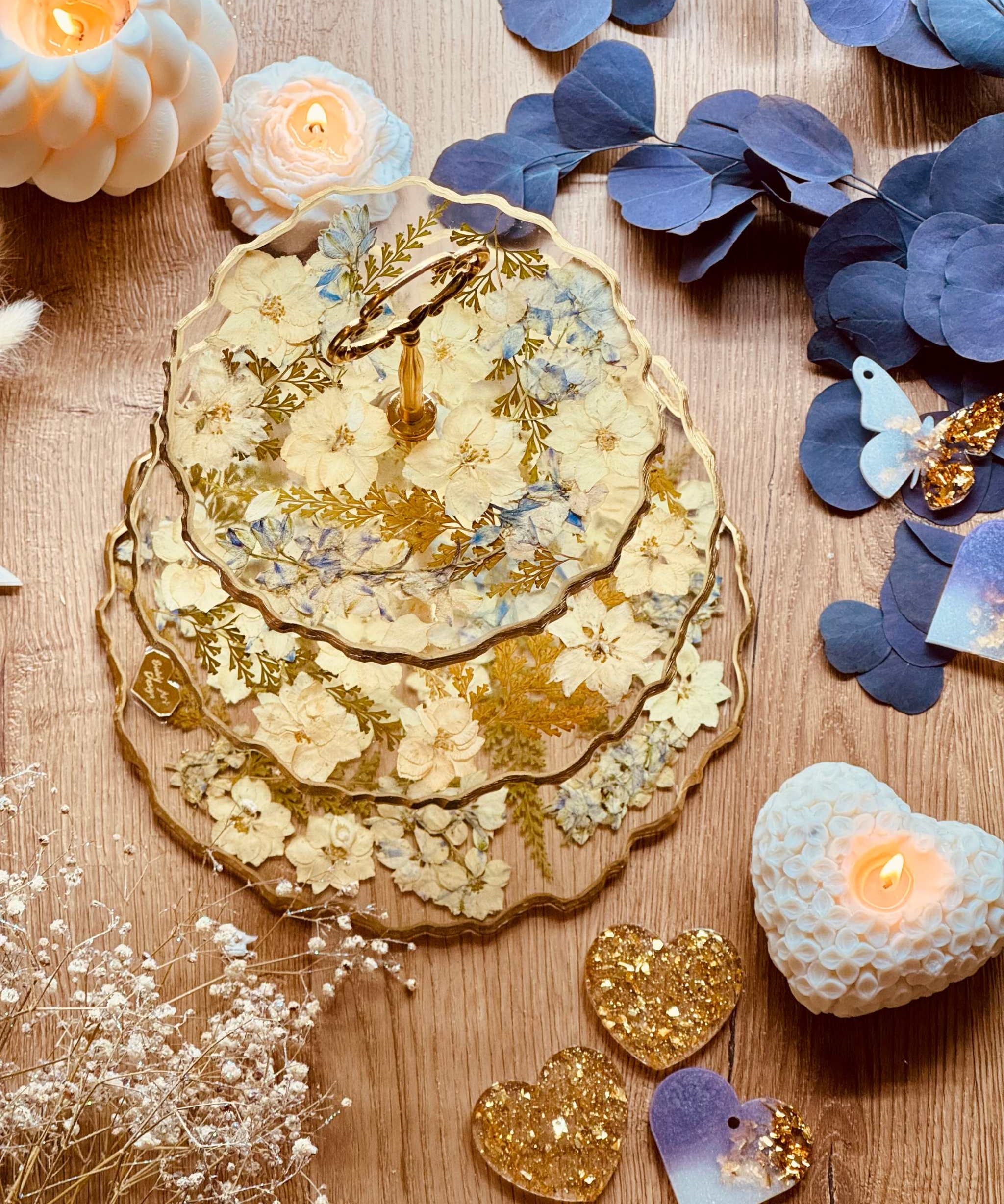 Romantischer Kuchenständer aus Epoxidharz mit pastelligen Trockenblumen, Farn und goldenen Akzenten – stilvolle Etagere in zartem Design