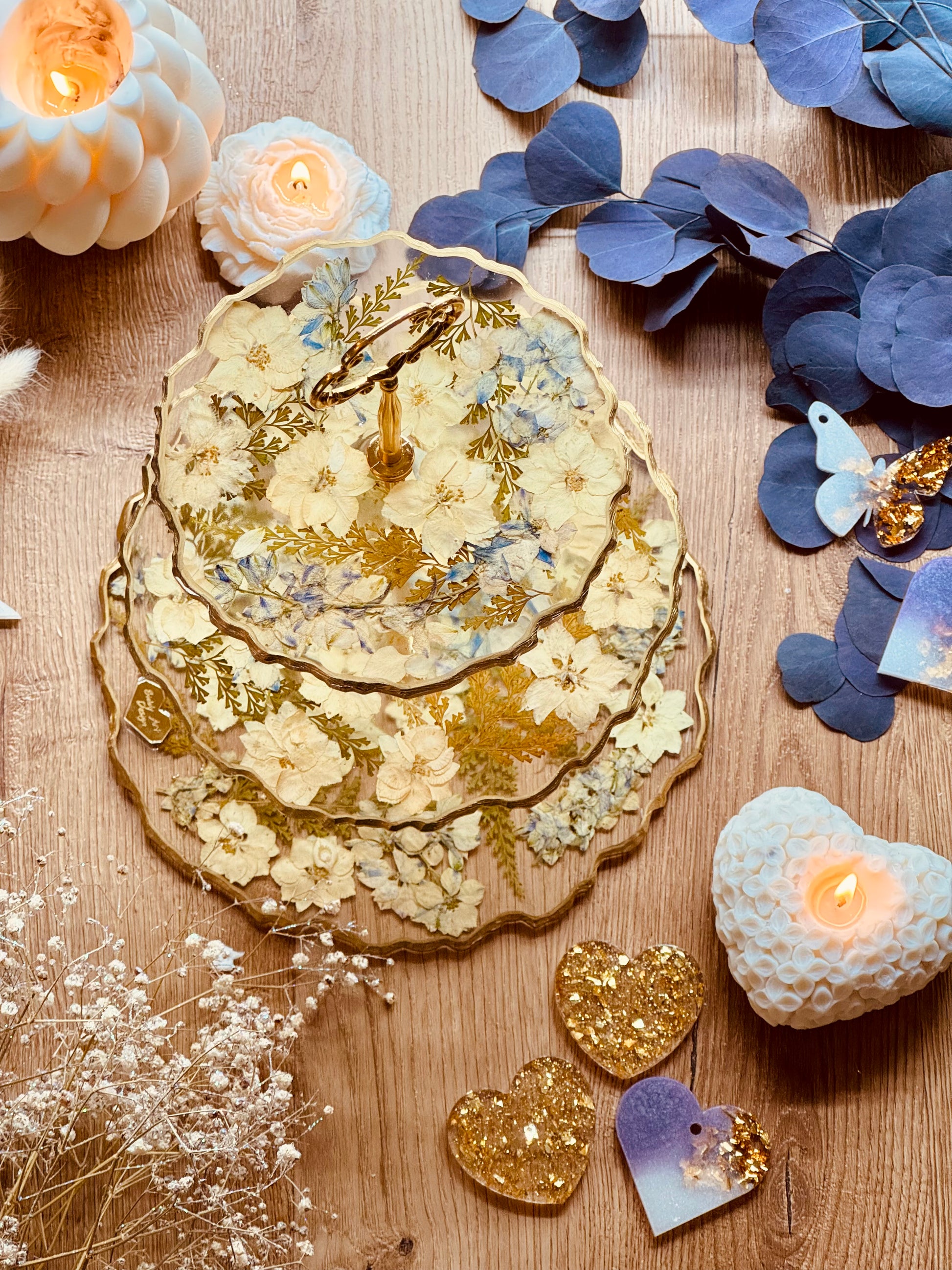 Romantischer Kuchenständer aus Epoxidharz mit pastelligen Trockenblumen, Farn und goldenen Akzenten – stilvolle Etagere in zartem Design