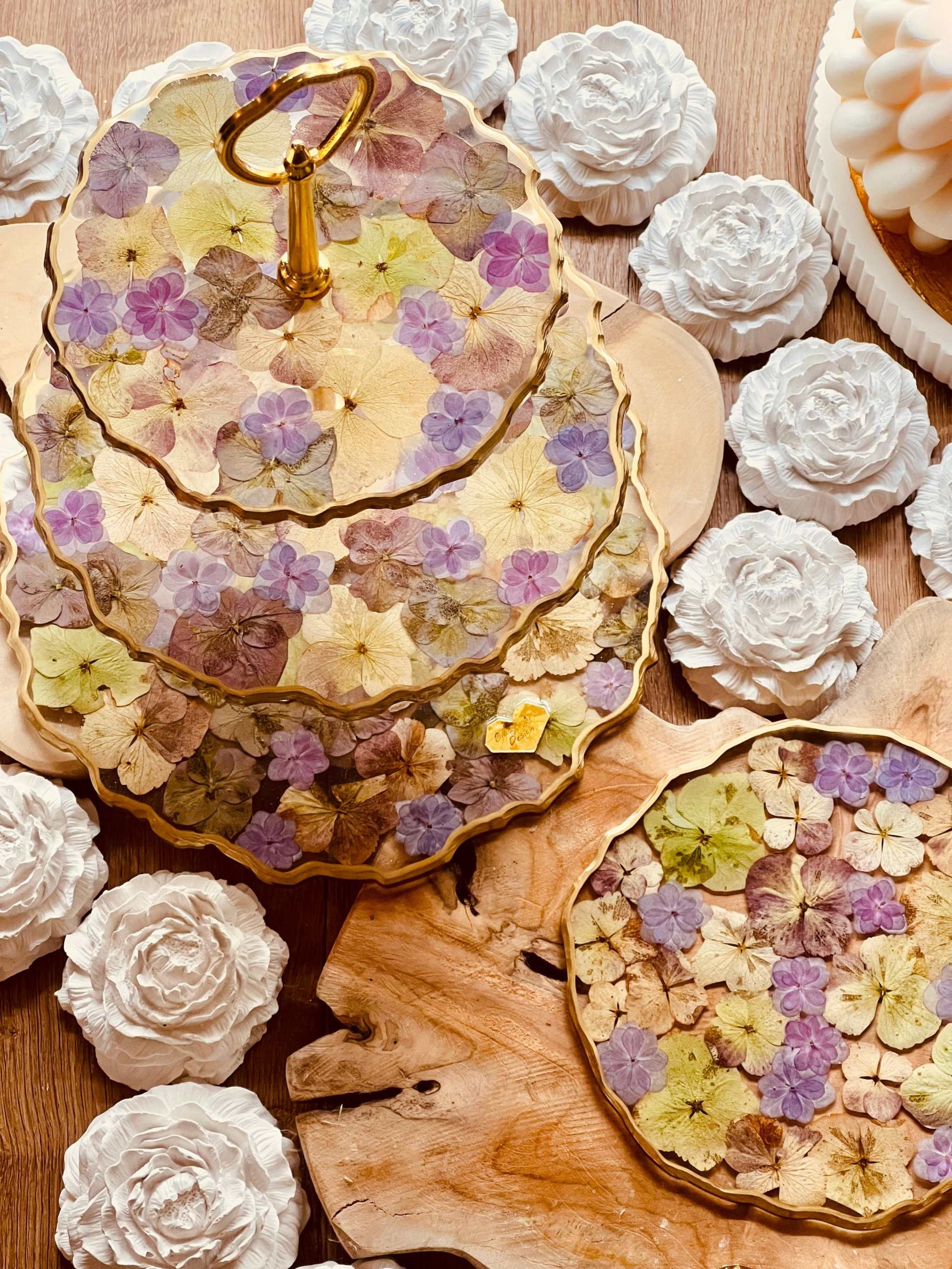 Exklusive Tischdekoration: Etagere aus Resin mit natürlichen und violetten Hortensienblüten und eleganten goldenen Akzenten.