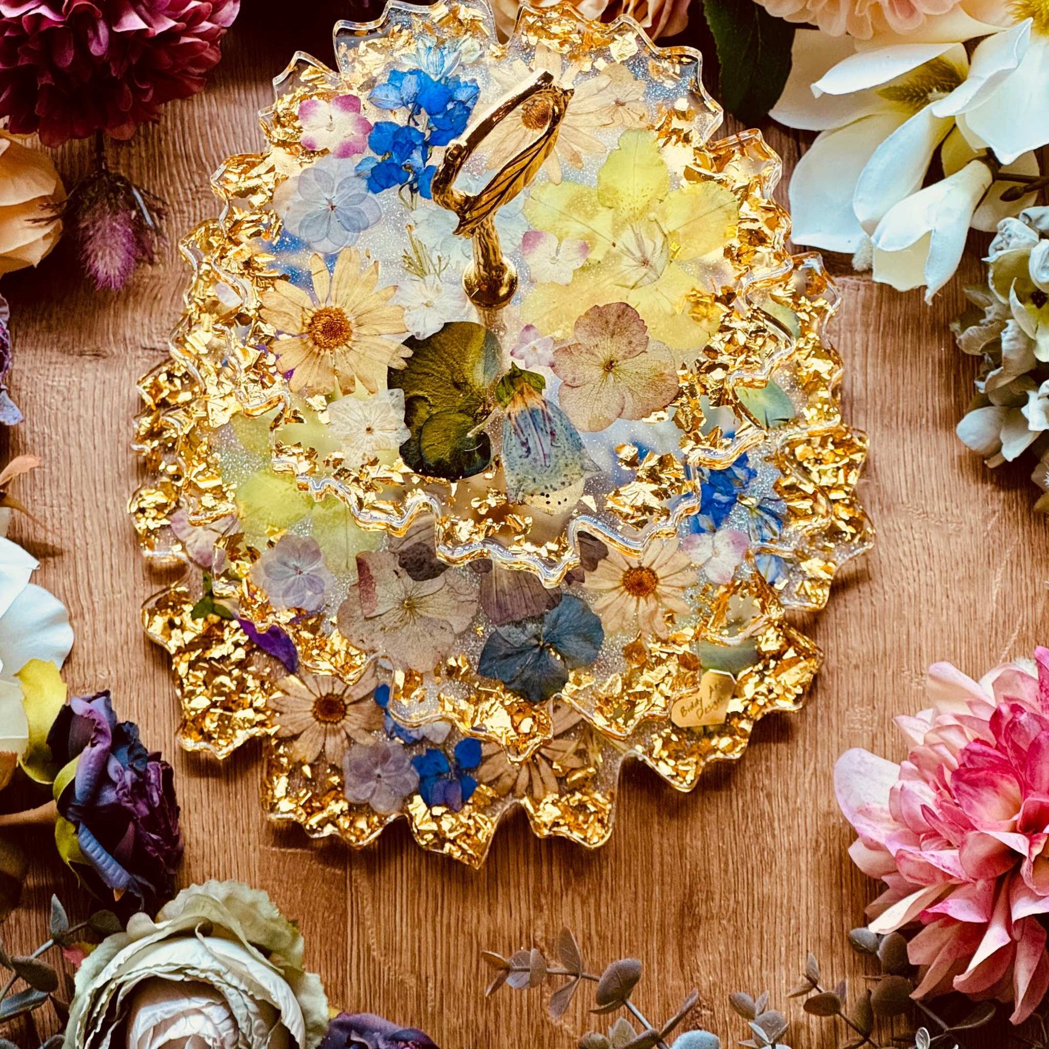 Epoxidharz Etagere mit echten Blumen und goldfarbenen Akzenten – geschwungener Kuchenständer aus Resin mit floraler Optik und glänzendem Blattgold