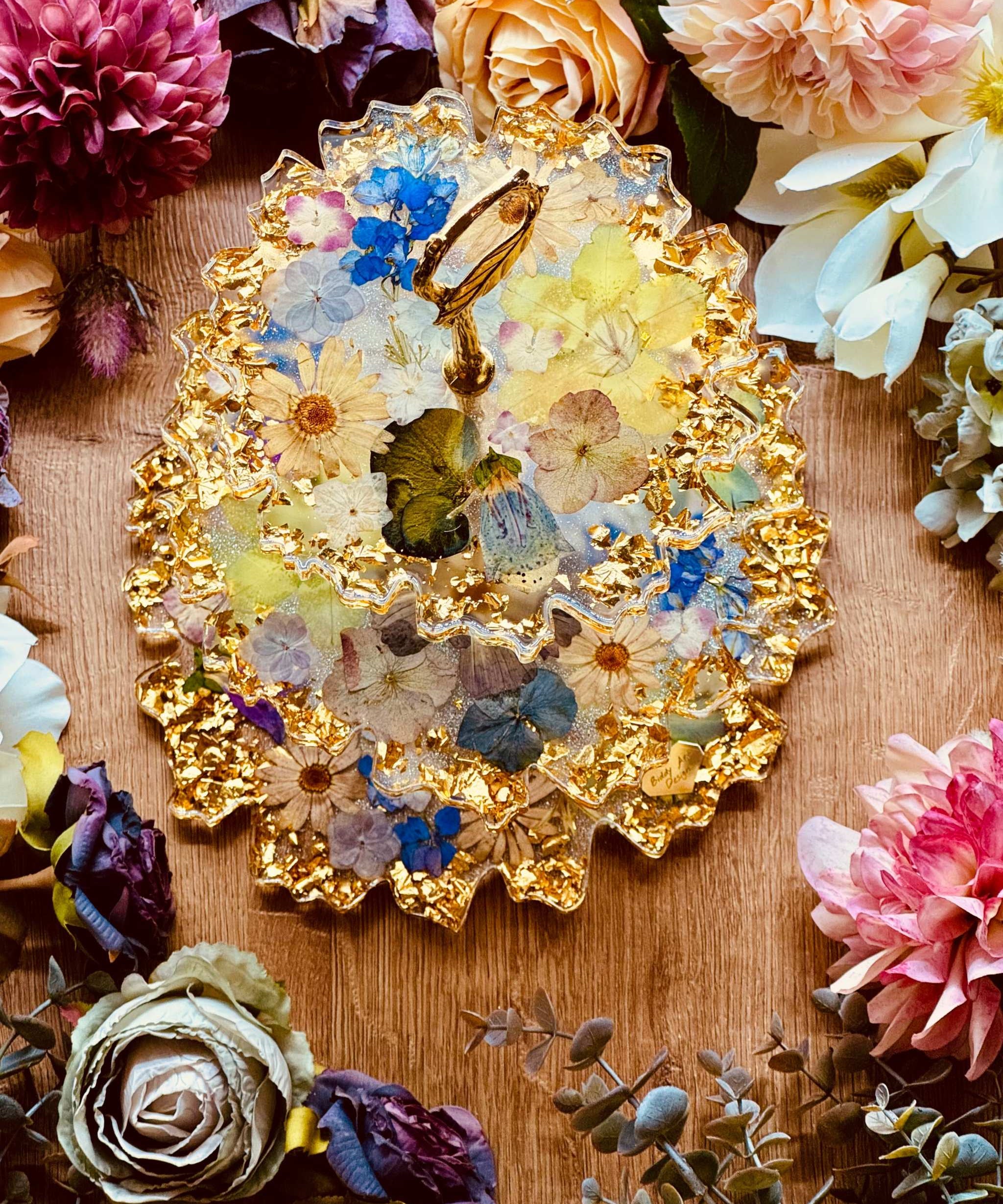 Epoxidharz Etagere mit echten Blumen und goldfarbenen Akzenten – geschwungener Kuchenständer aus Resin mit floraler Optik und glänzendem Blattgold