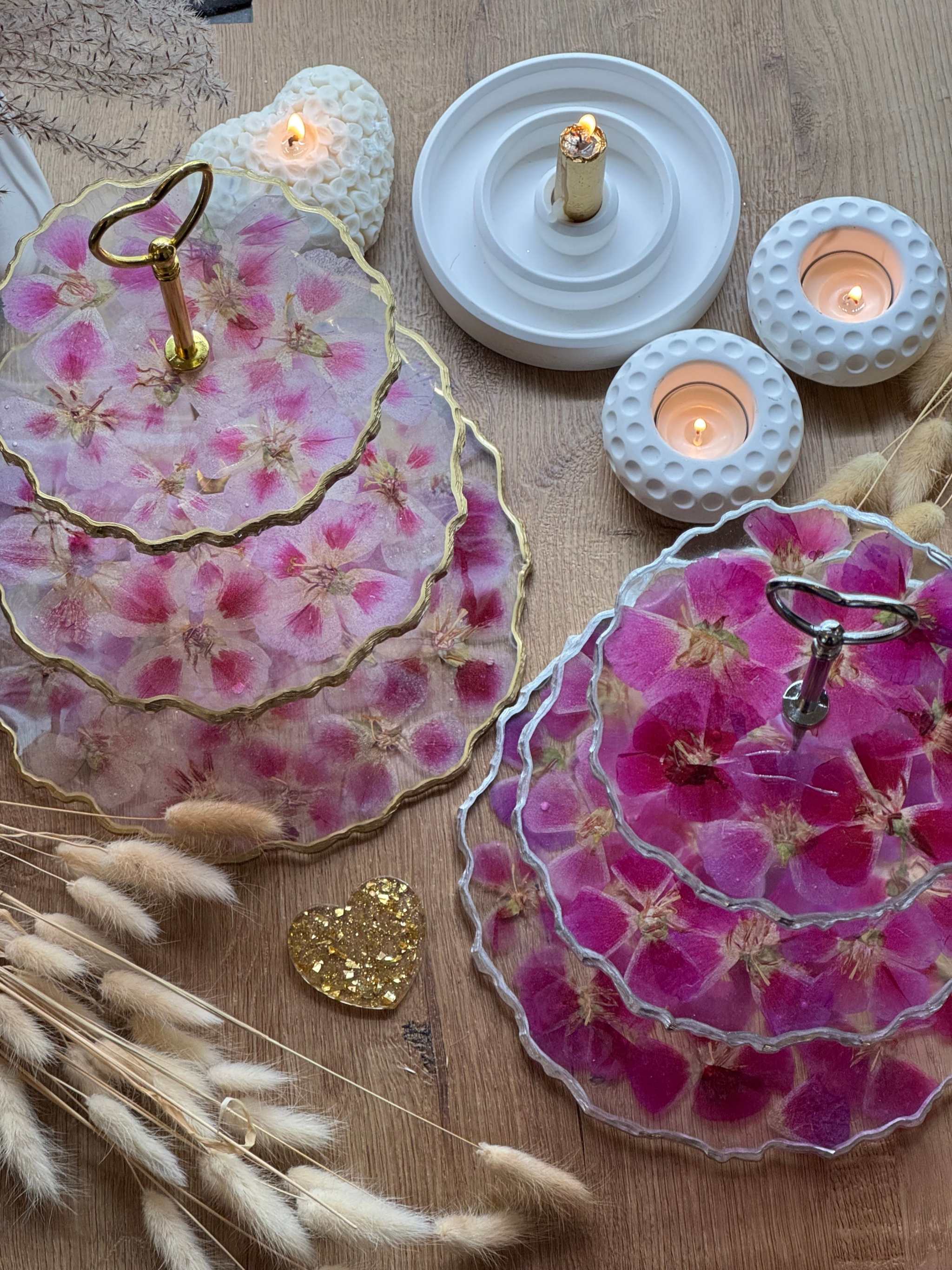 Epoxidharz Etagere aus Resin mit pinken und rosa Blüten, goldenen und silbernen Details, auf Holztisch mit Kerzen.