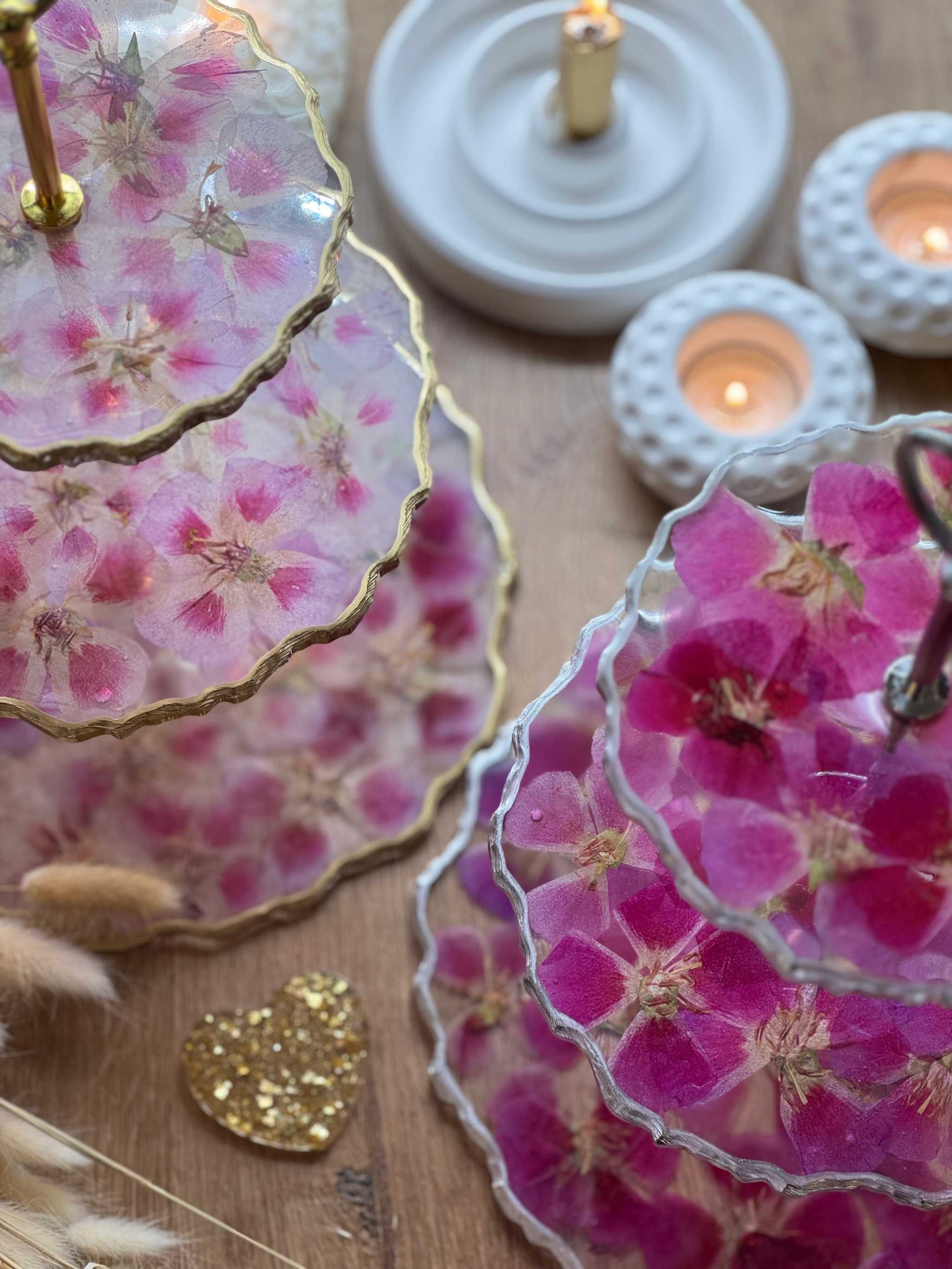 Epoxidharz Etagere aus Resin mit pinken und rosa Blüten und goldenen Details auf Holztisch mit Kerzen.