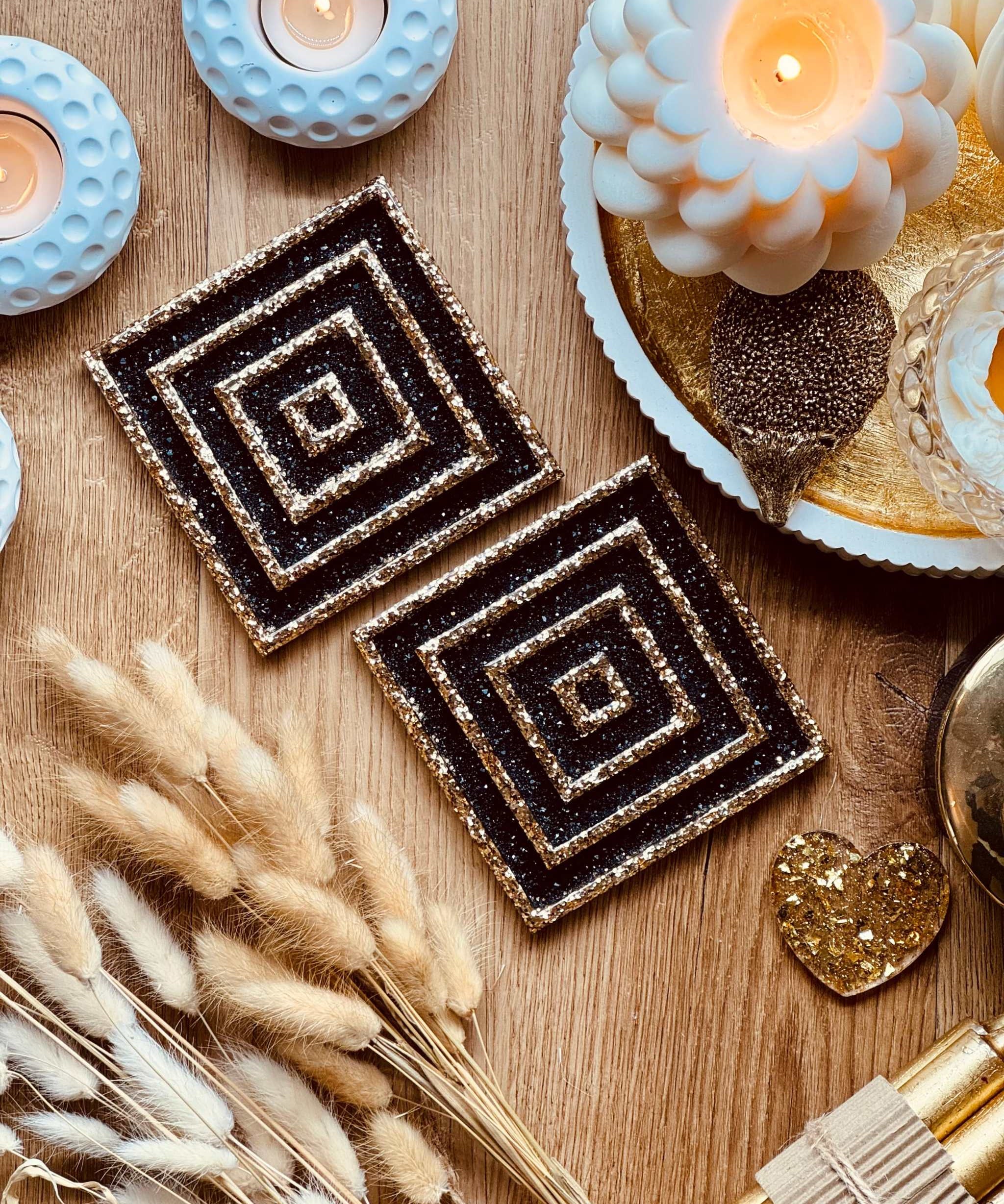 2 Untersetzer aus Resin in Schwarz mit goldenem 3D Design, handgemacht, 10x10cm, dekorativ auf Holztisch mit Kerzen und Dekoarrangement