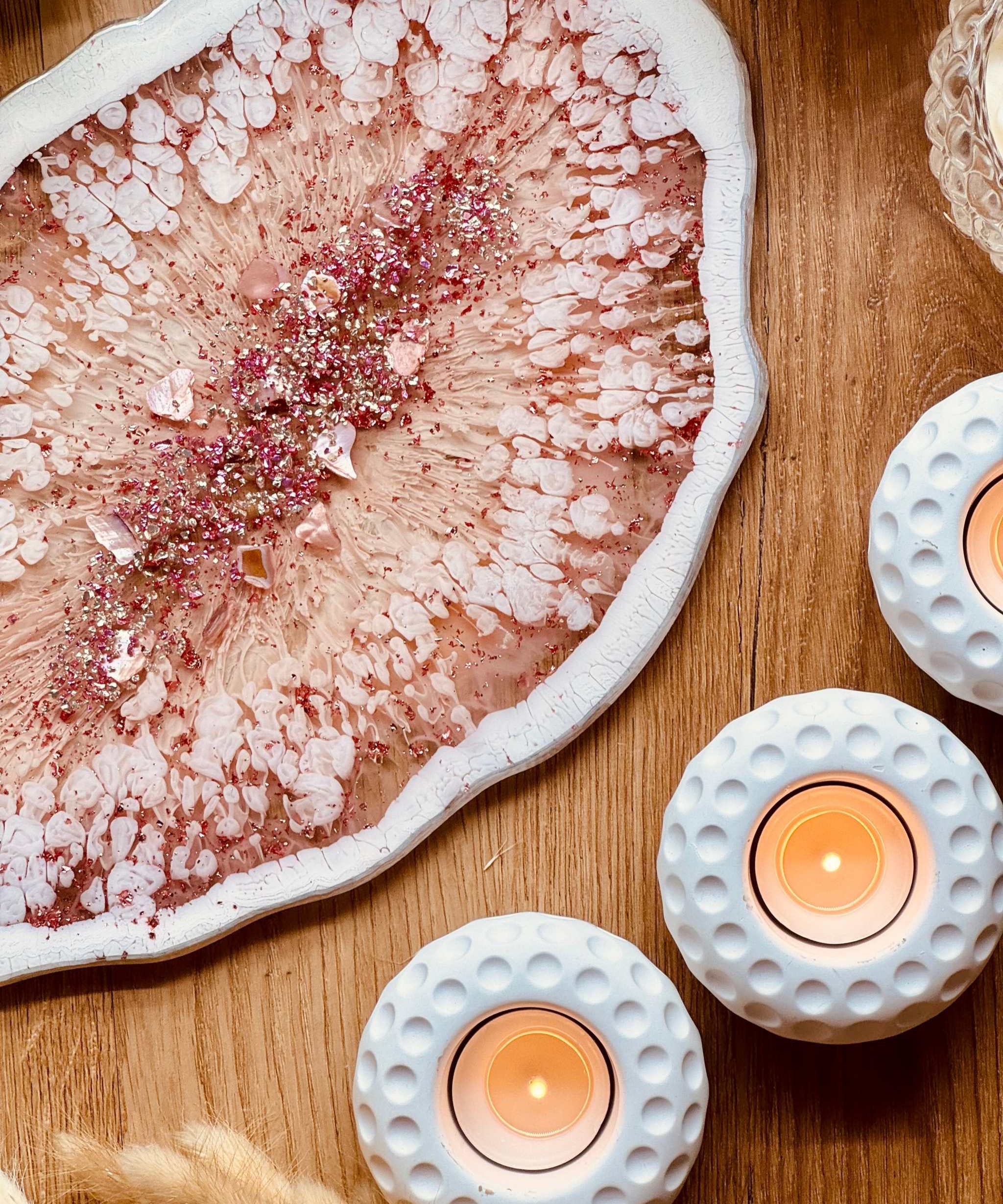 Handgemachtes rosa Tablett aus Resin mit silbernen Details auf Holzoberfläche neben Kerzenhaltern