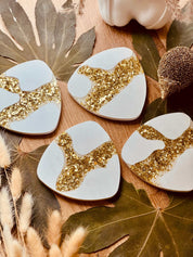 Set aus vier einzigartigen Untersetzern aus Gießkeramik mit goldenen Harzdetails, ideal für ein gehobenes Wohnambiente und als Geschenkidee.Funkelnde Weisse Deko Giesskeramik Untersetzer Blattgold