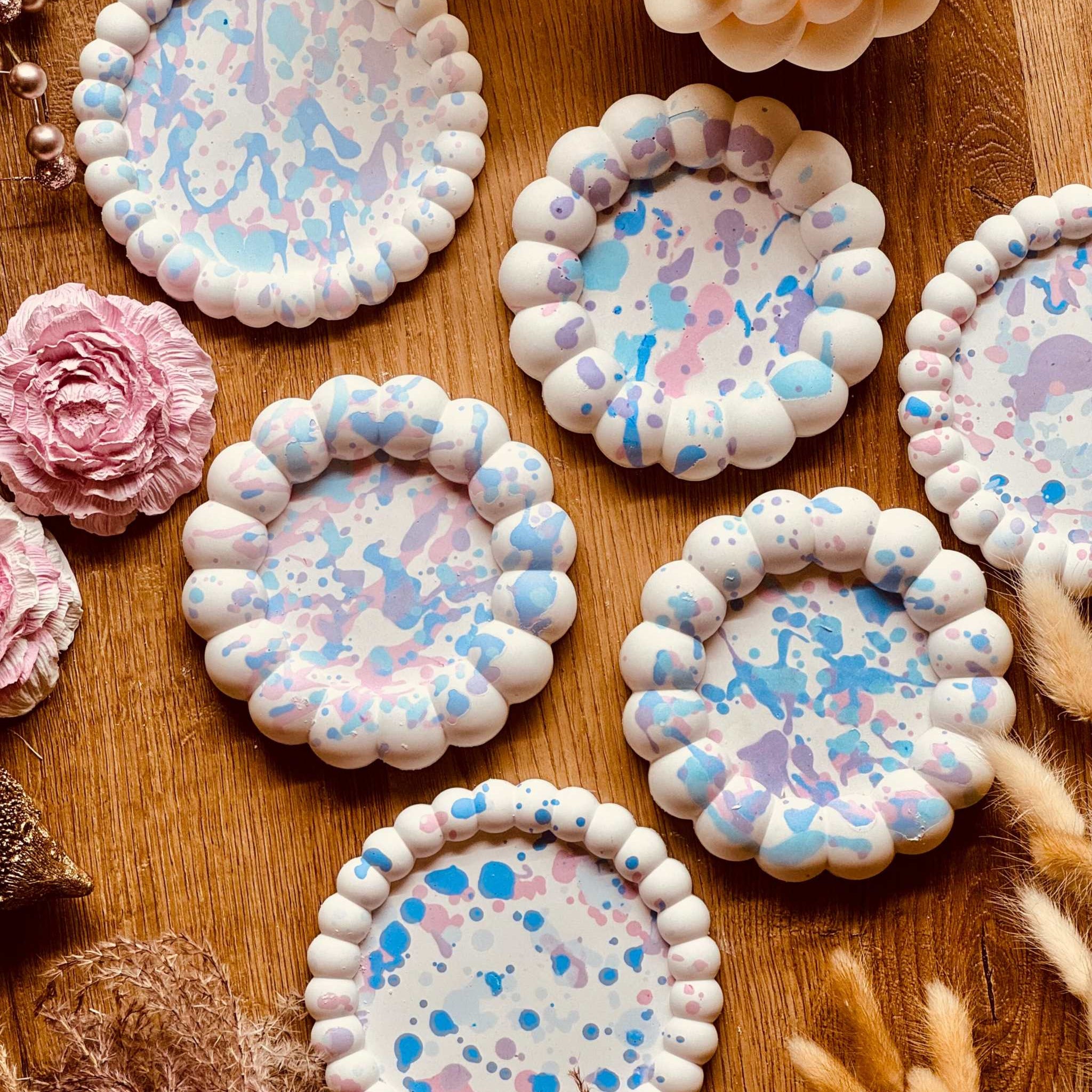 Runde Untersetzer aus Gießkeramik mit gewelltem Rand und buntem Sprenkelmuster in Pastelltönen, einzeln erhältlich, ideal für Getränke oder als Kerzenteller.