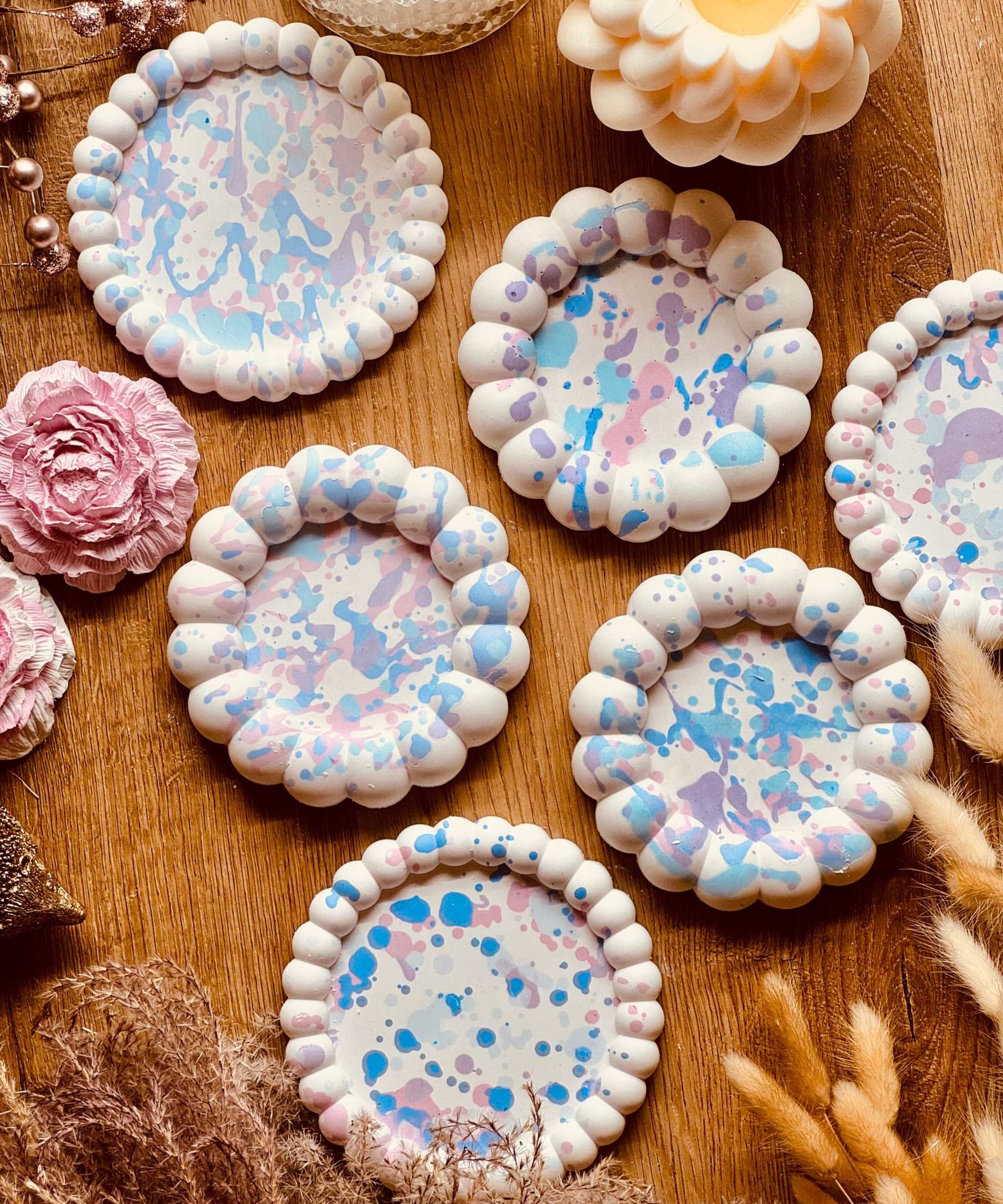 Runde Untersetzer aus Gießkeramik mit gewelltem Rand und buntem Sprenkelmuster in Pastelltönen, einzeln erhältlich, ideal für Getränke oder als Kerzenteller.