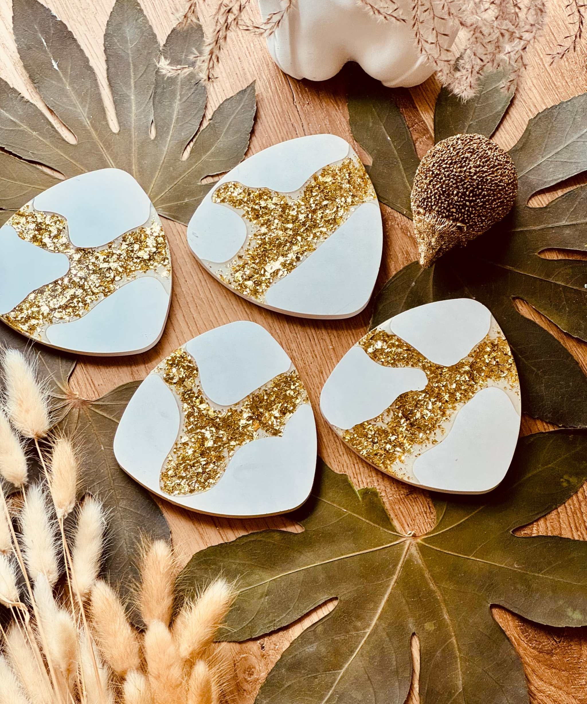 Handgefertigte Gießkeramik-Untersetzer im 4er-Set, verziert mit kunstvollen goldenen Harz-Details, perfekt für stilvolle Getränkeunterlagen.Giesskeramik Weisse Deko Untersetzer mit Blattgold Glanz