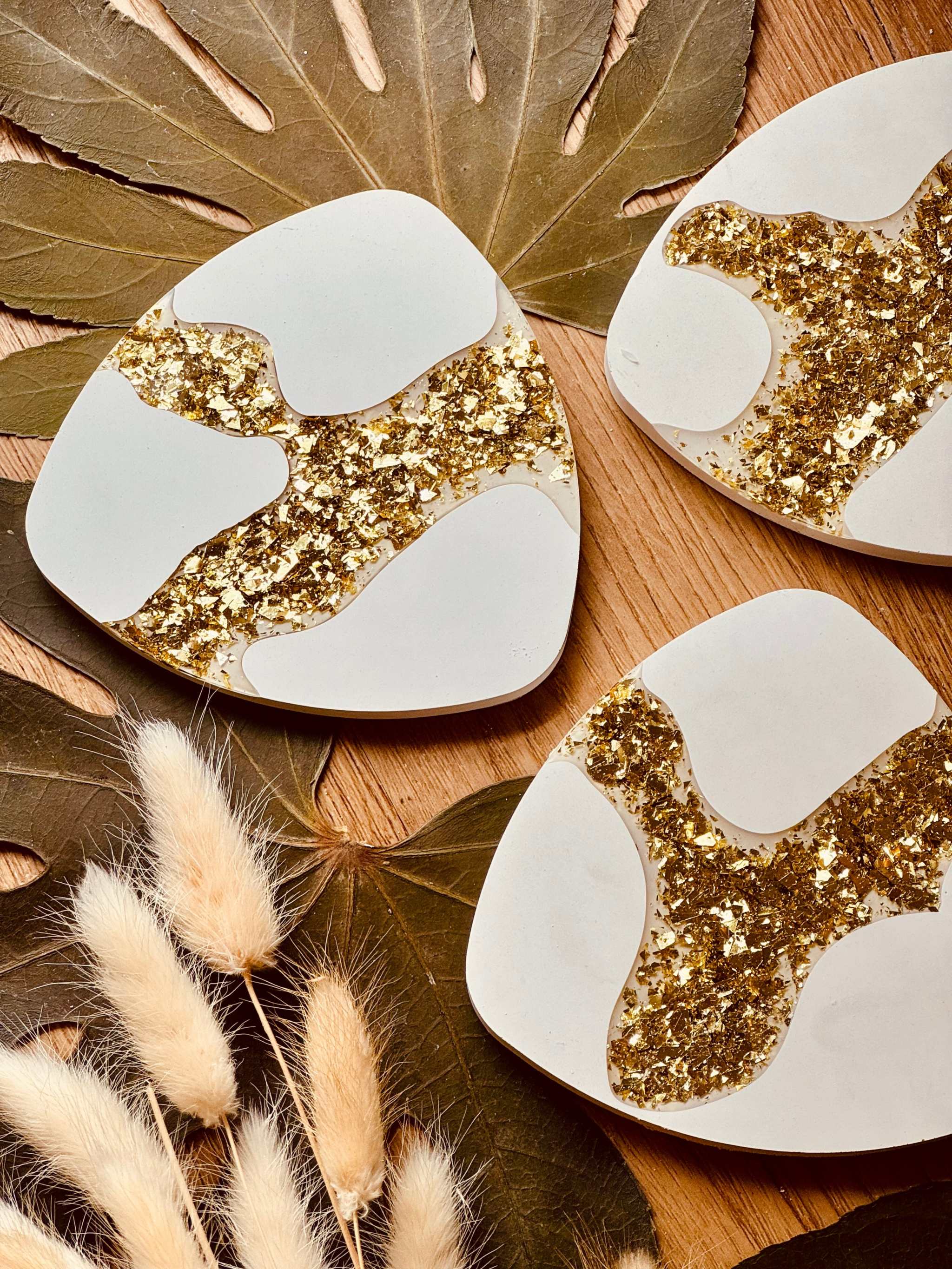 Gießkeramik-Untersetzer im 4er-Set mit glitzernden Gold-Resin-Akzenten, handgefertigt und perfekt, um Tische vor Getränkeflecken zu schützen.Glitzernder Blattgold Untersetzer Giesskeramik Weisse Deko