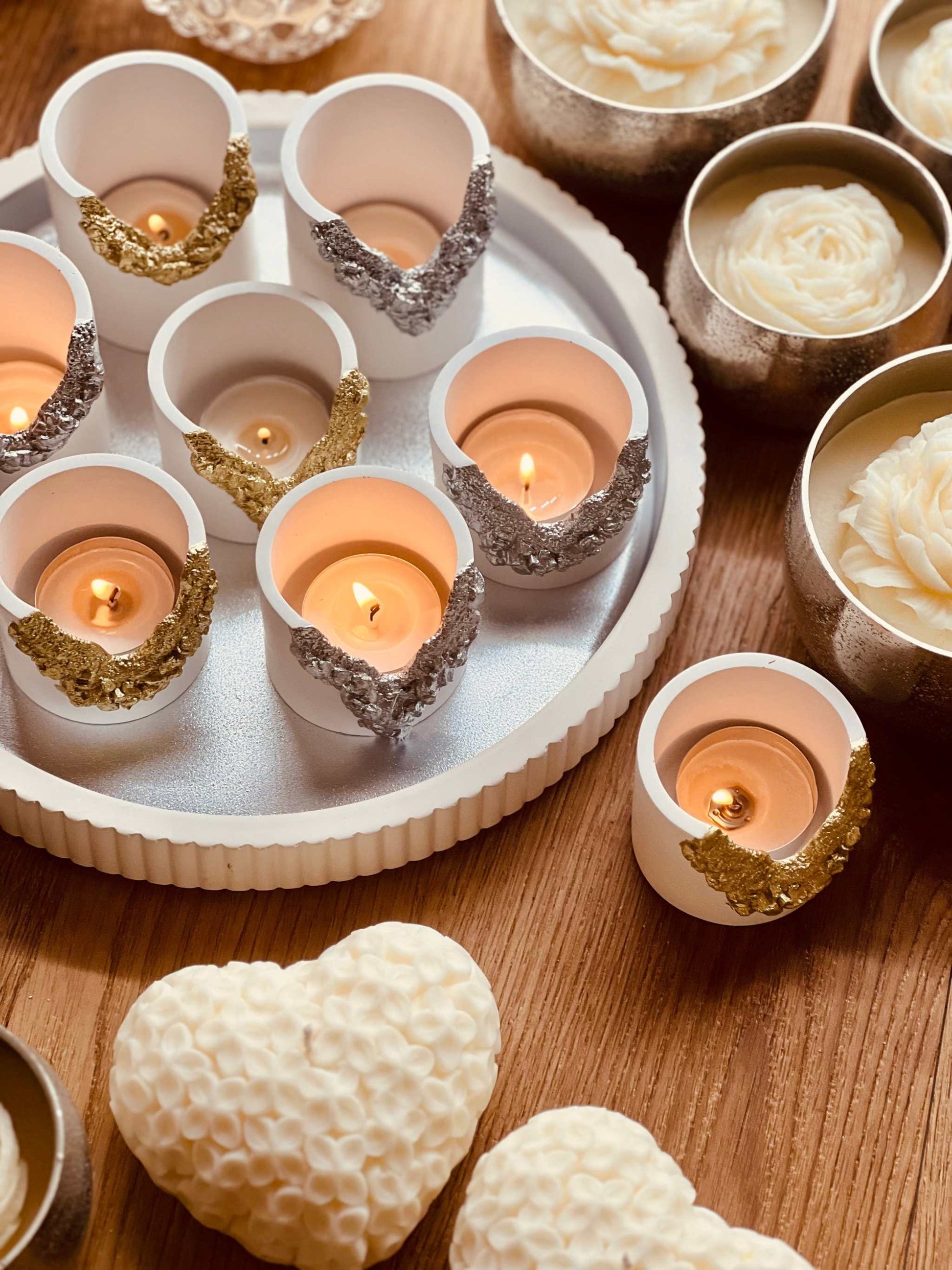 Handcrafted Gießkeramik tealight holders with gold and silver accents displayed on a wooden surface.