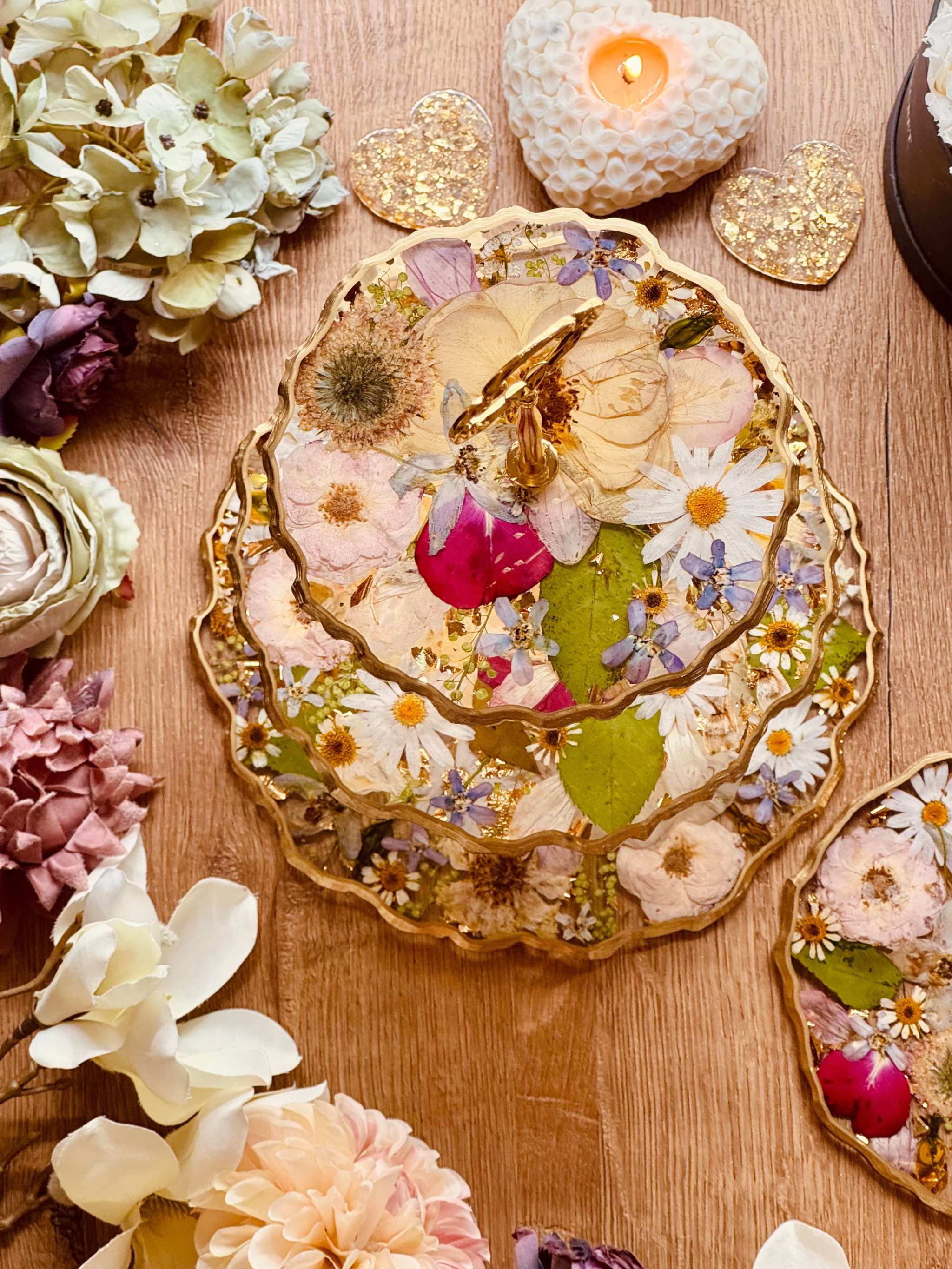 Handgefertigte Etagere aus konservierten Brautstraußblüten mit floralen Details und goldenen Akzenten auf Holztisch