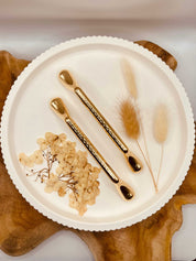 Gold-colored tablet grips set "The Solid One" on a decorative plate with dried flowers.