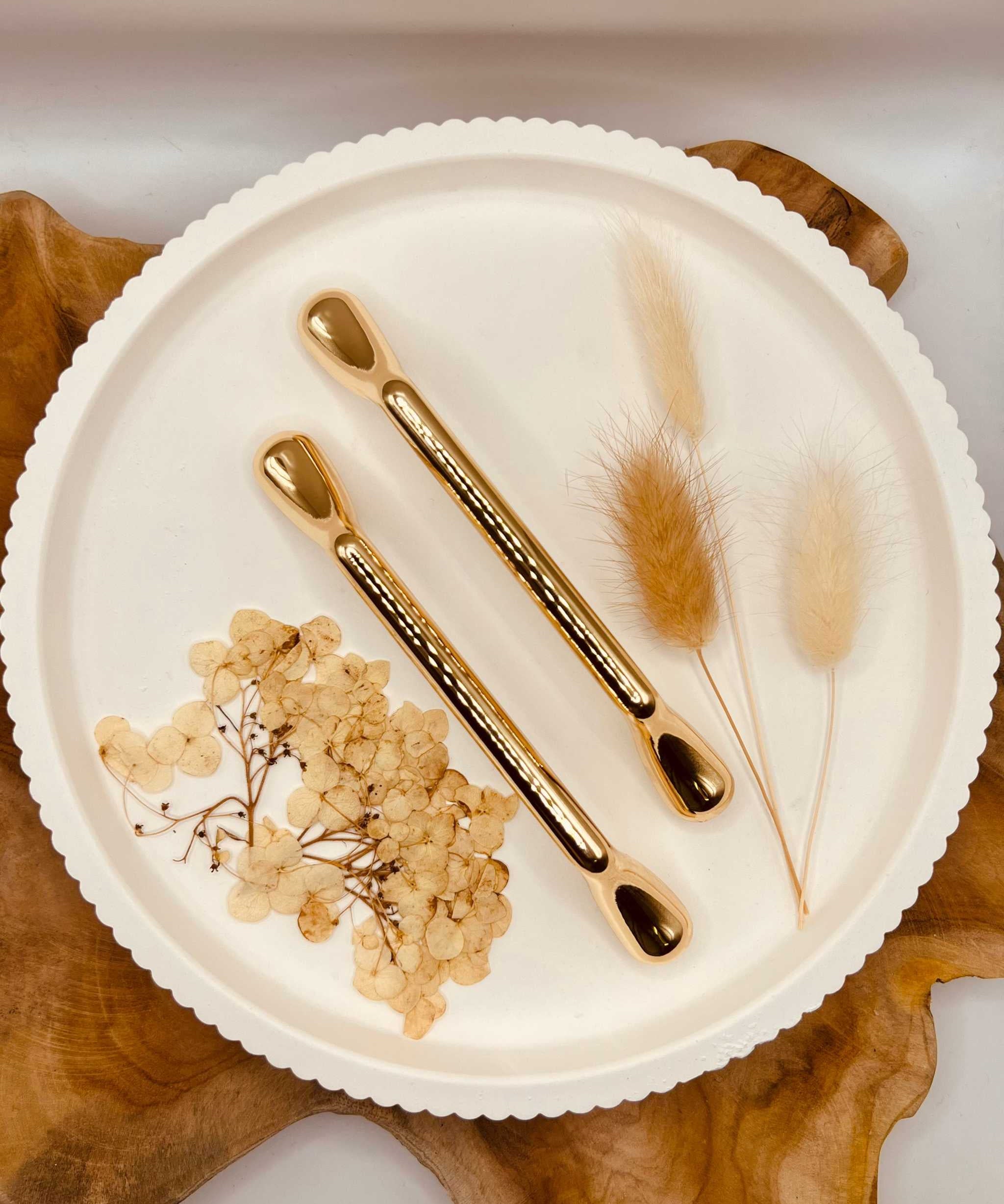 Gold-colored tablet grips set "The Solid One" on a decorative plate with dried flowers.