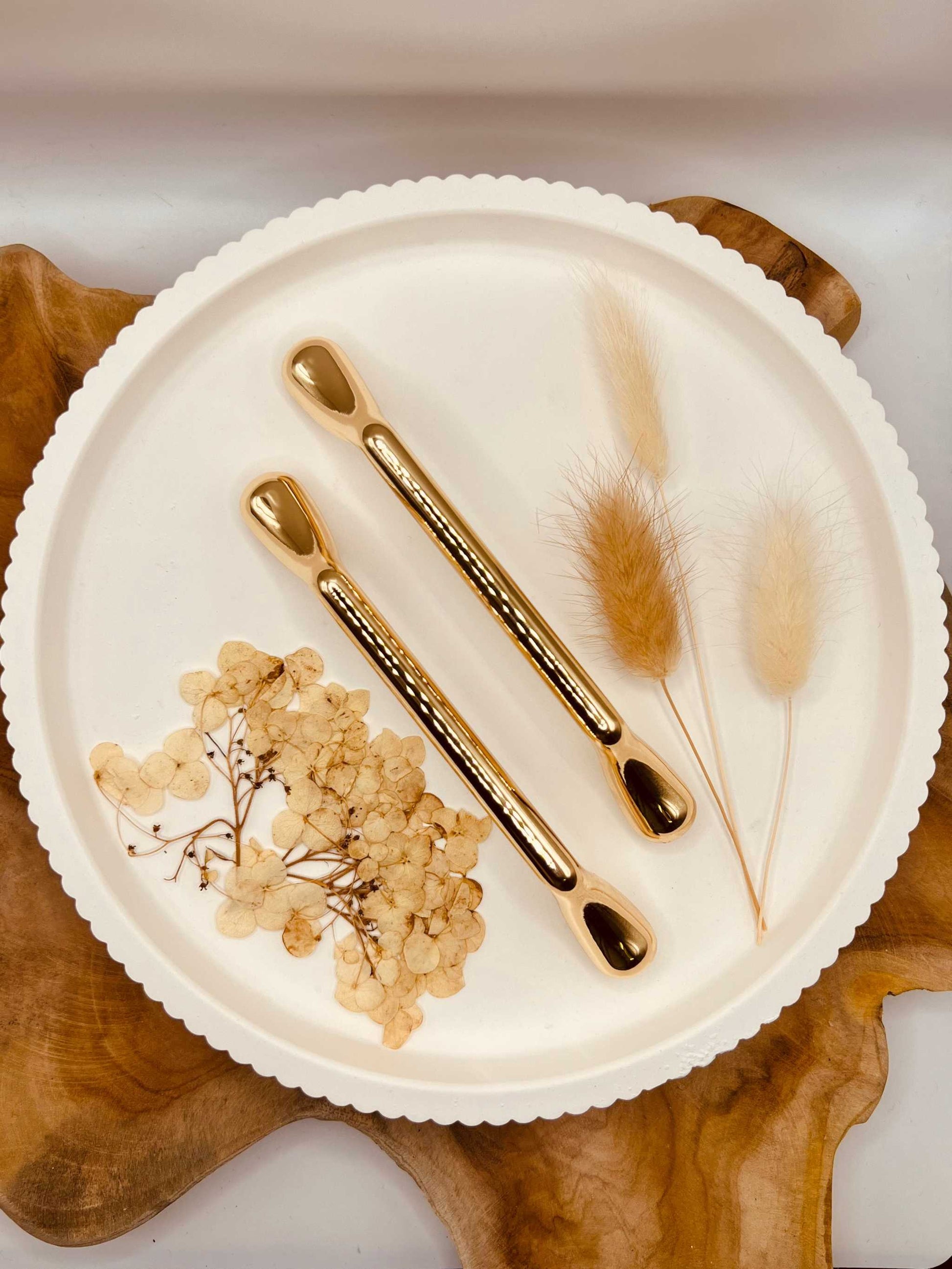 Gold-colored tablet grips set "The Solid One" on a decorative plate with dried flowers.