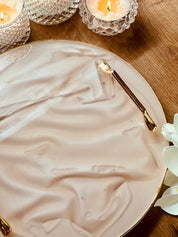 Golden tablet handle set "The Solid One" on elegant tray with candles and flowers.