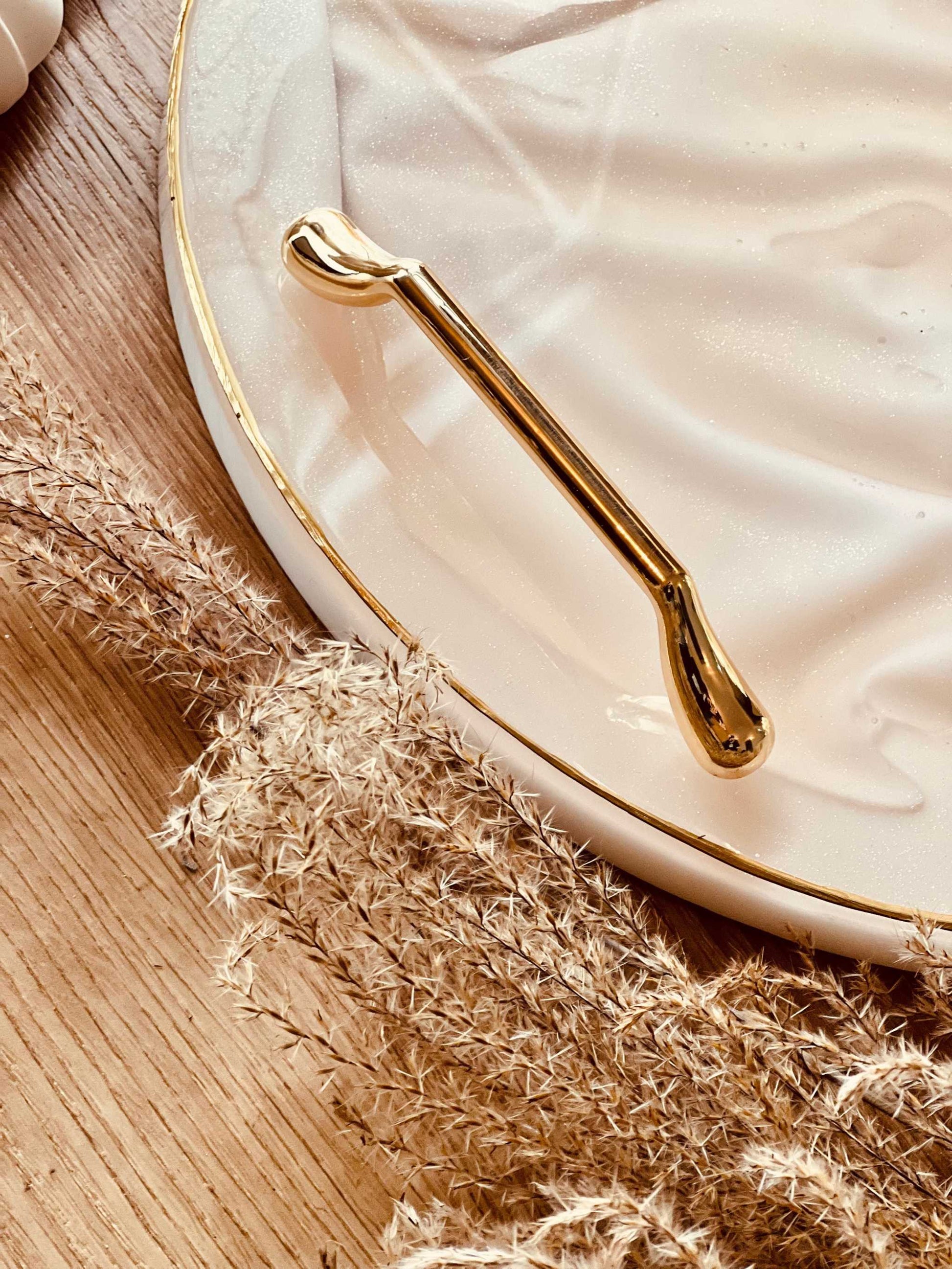Goldfarbenes Tablettgriff-Set “The Solid One” auf weißer Oberfläche mit natürlicher Dekoration.