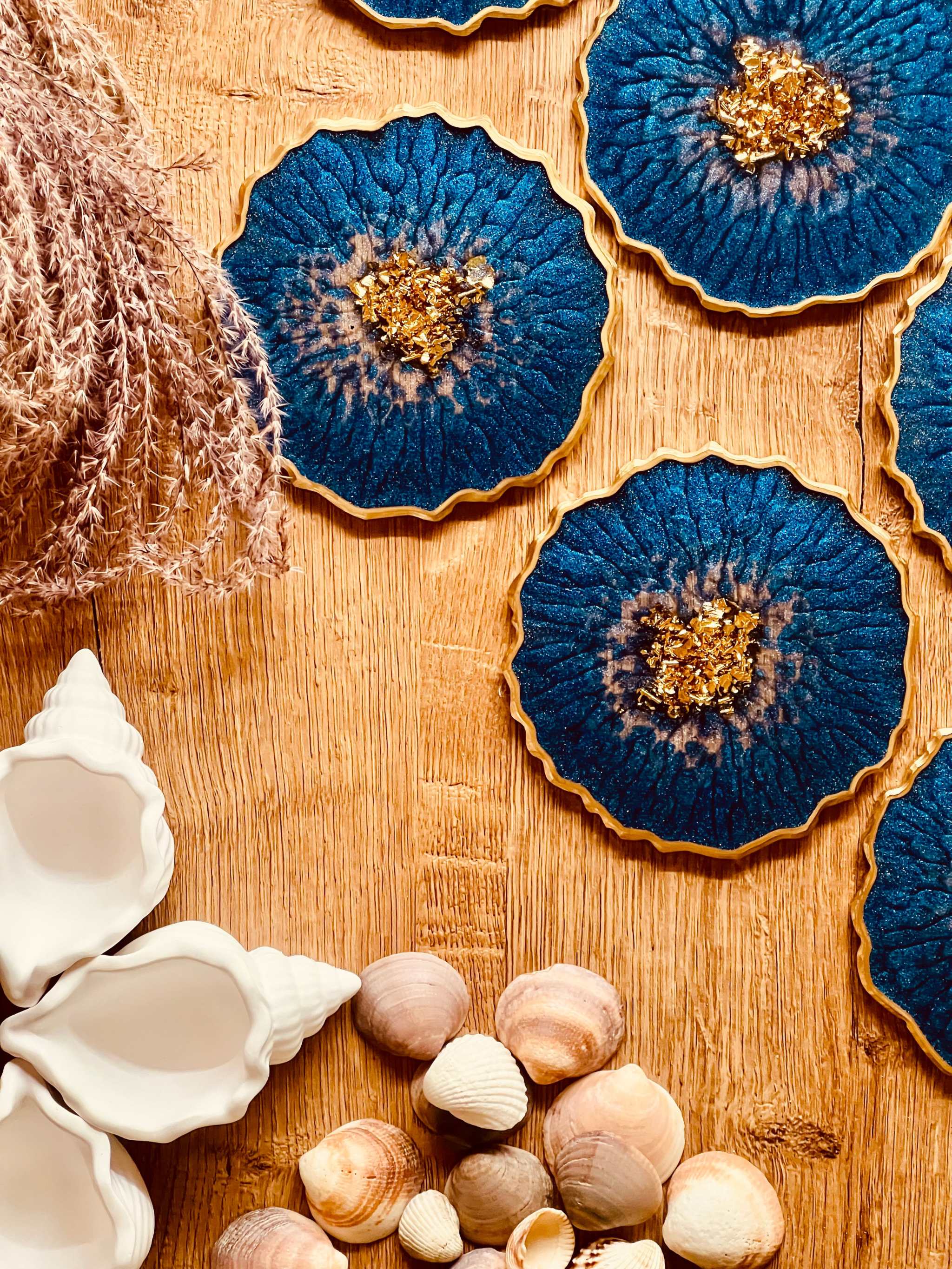 6 handgemachte Untersetzer aus blauem Resin mit goldenen Details und 12cm Durchmesser auf Holzuntergrund