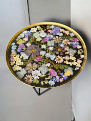 Kunstvoller Epoxidharz Couchtisch mit dekorativer Blütenplatte, gefasst in Goldrand, auf schwarzem Metallgestell – floral, bunt und edel